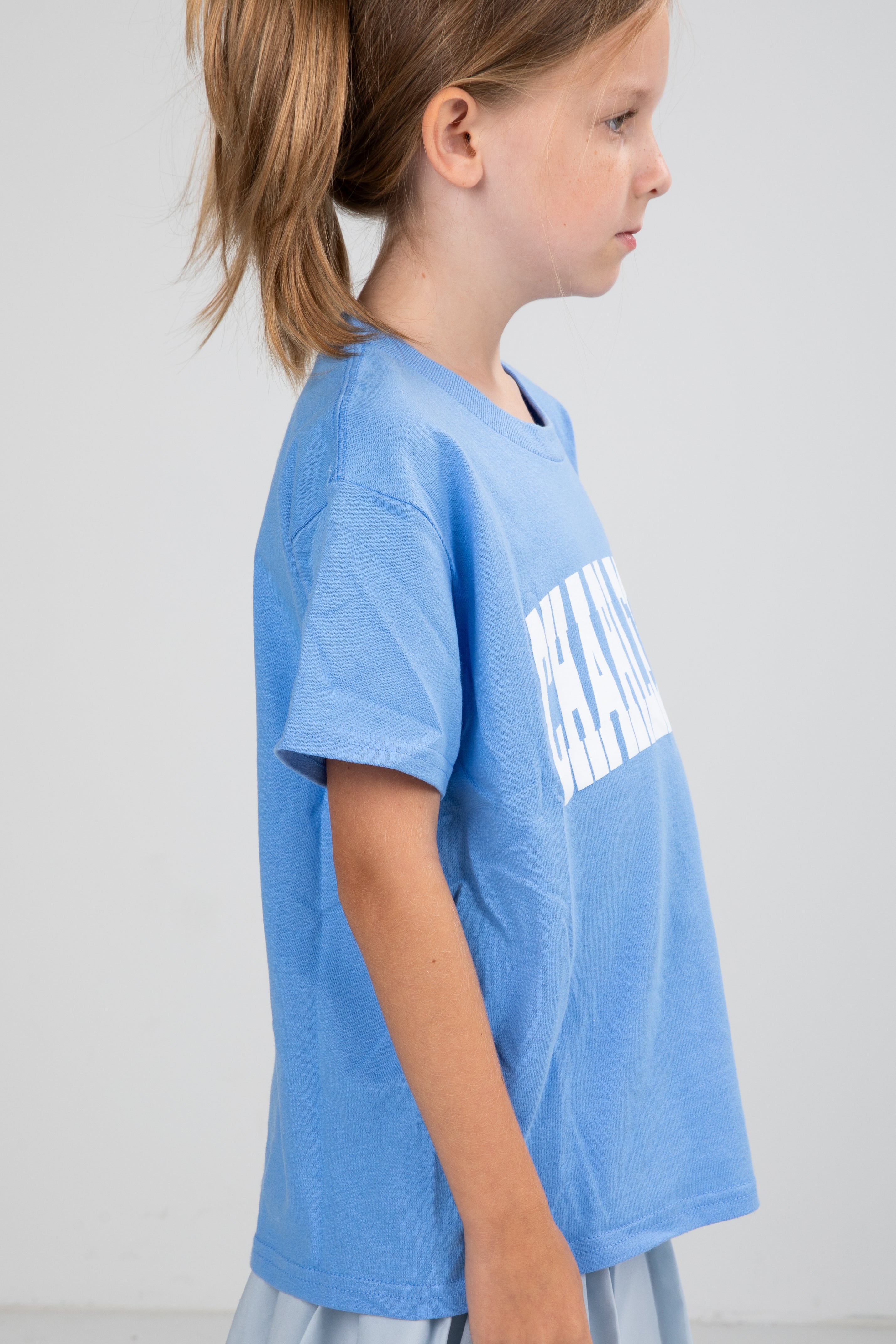 Child wearing a blue t-shirt with white text on a plain background