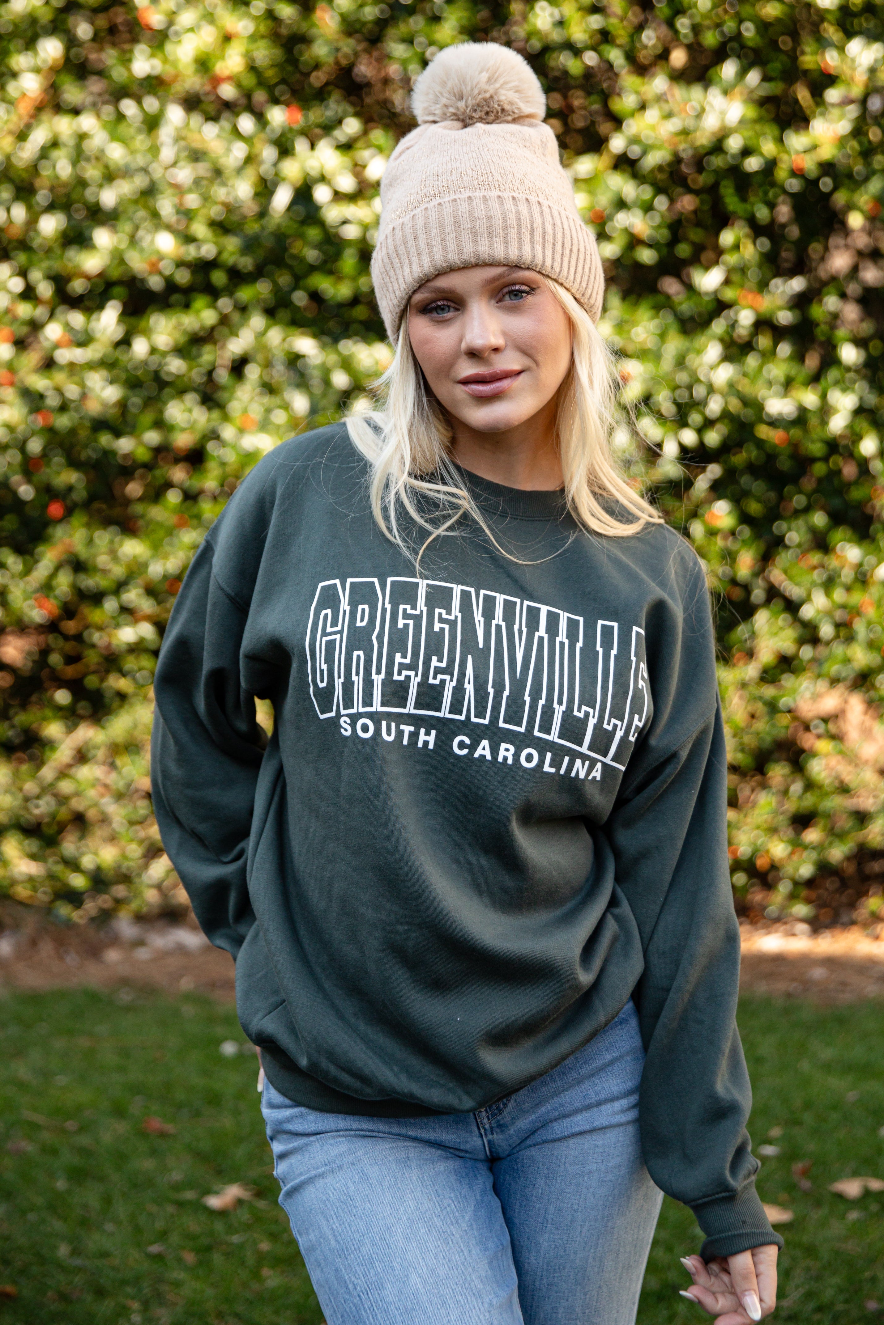 Woman wearing a dark green sweatshirt with &