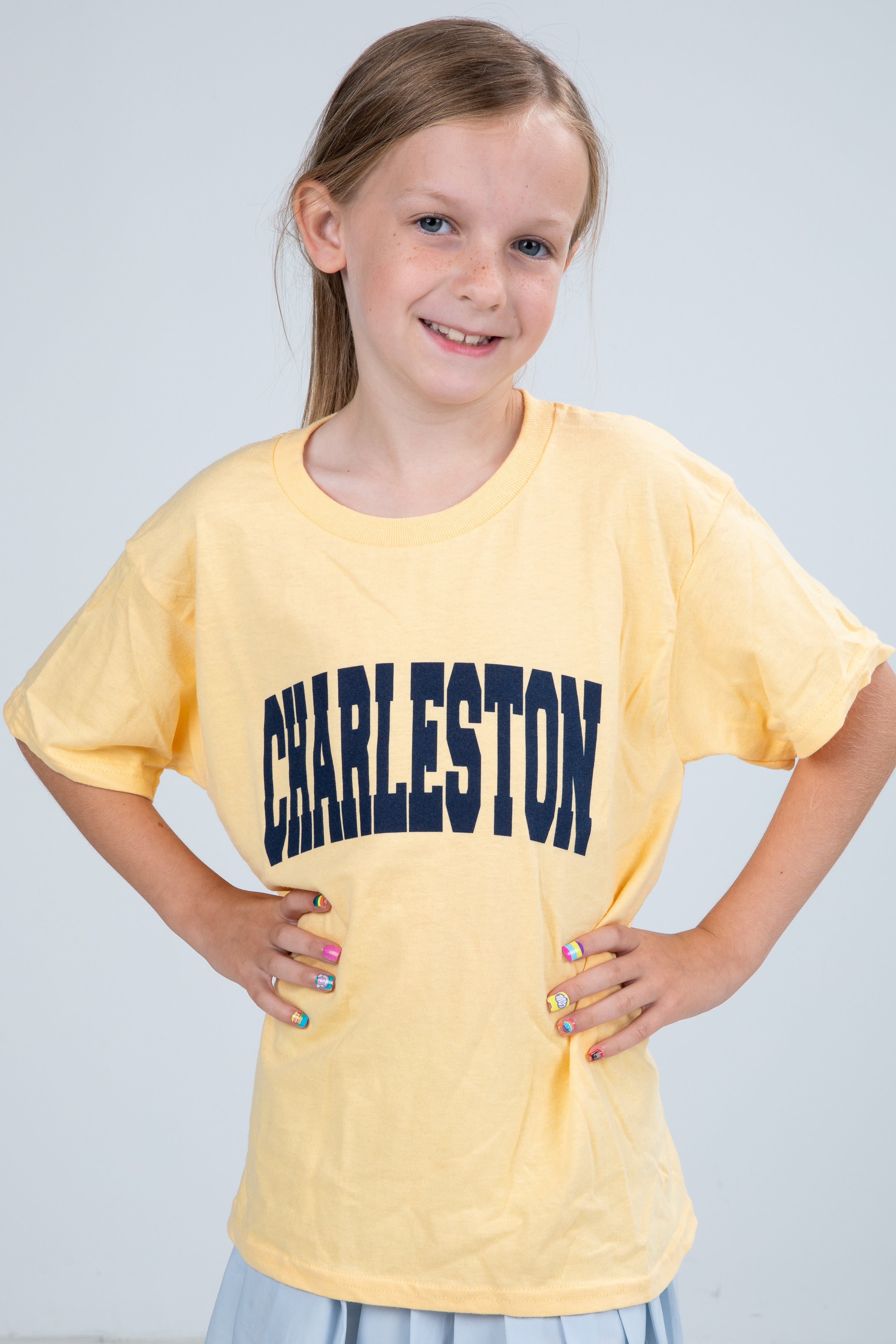 Young girl wearing a yellow t-shirt with &