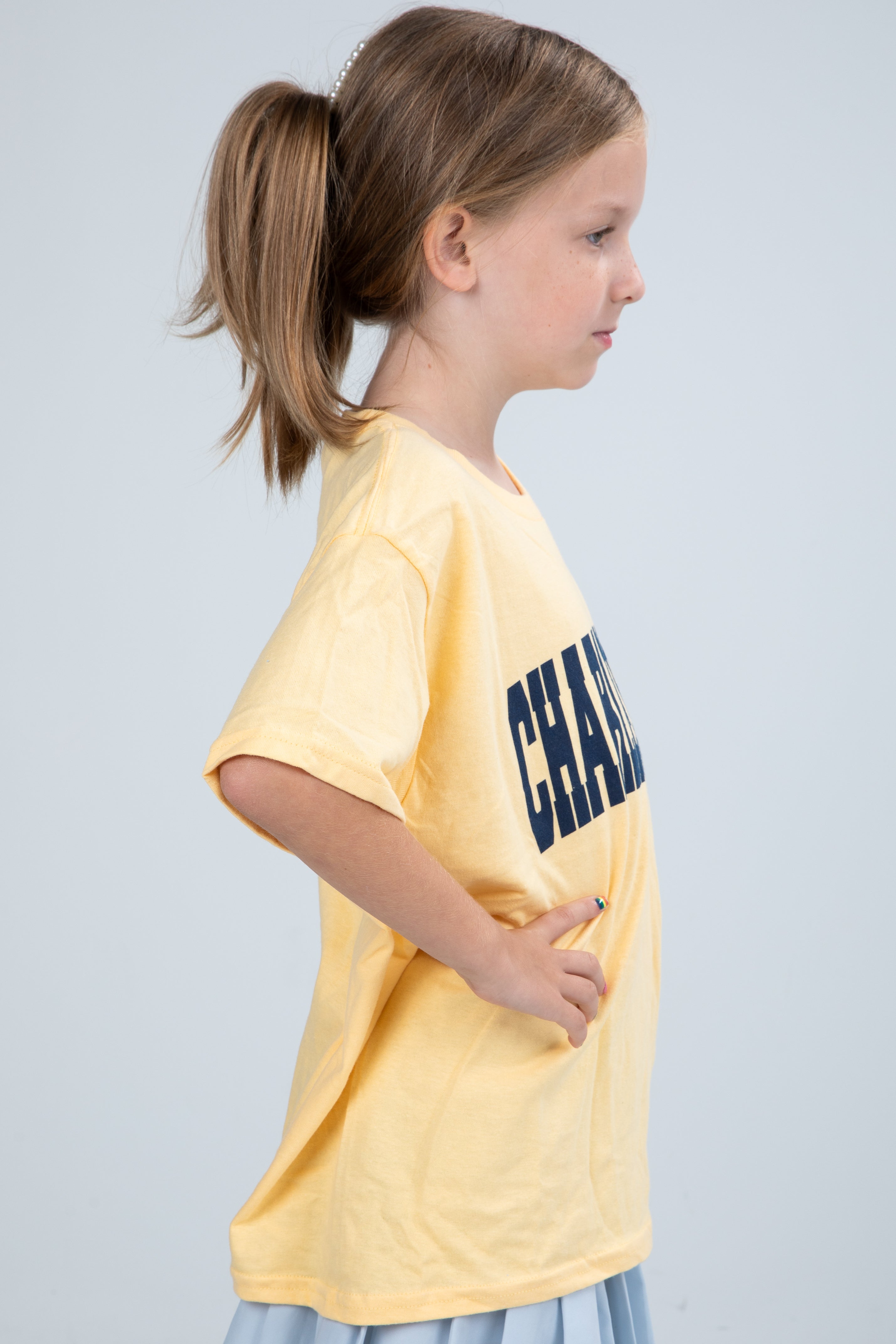 Young girl wearing a yellow t-shirt with &