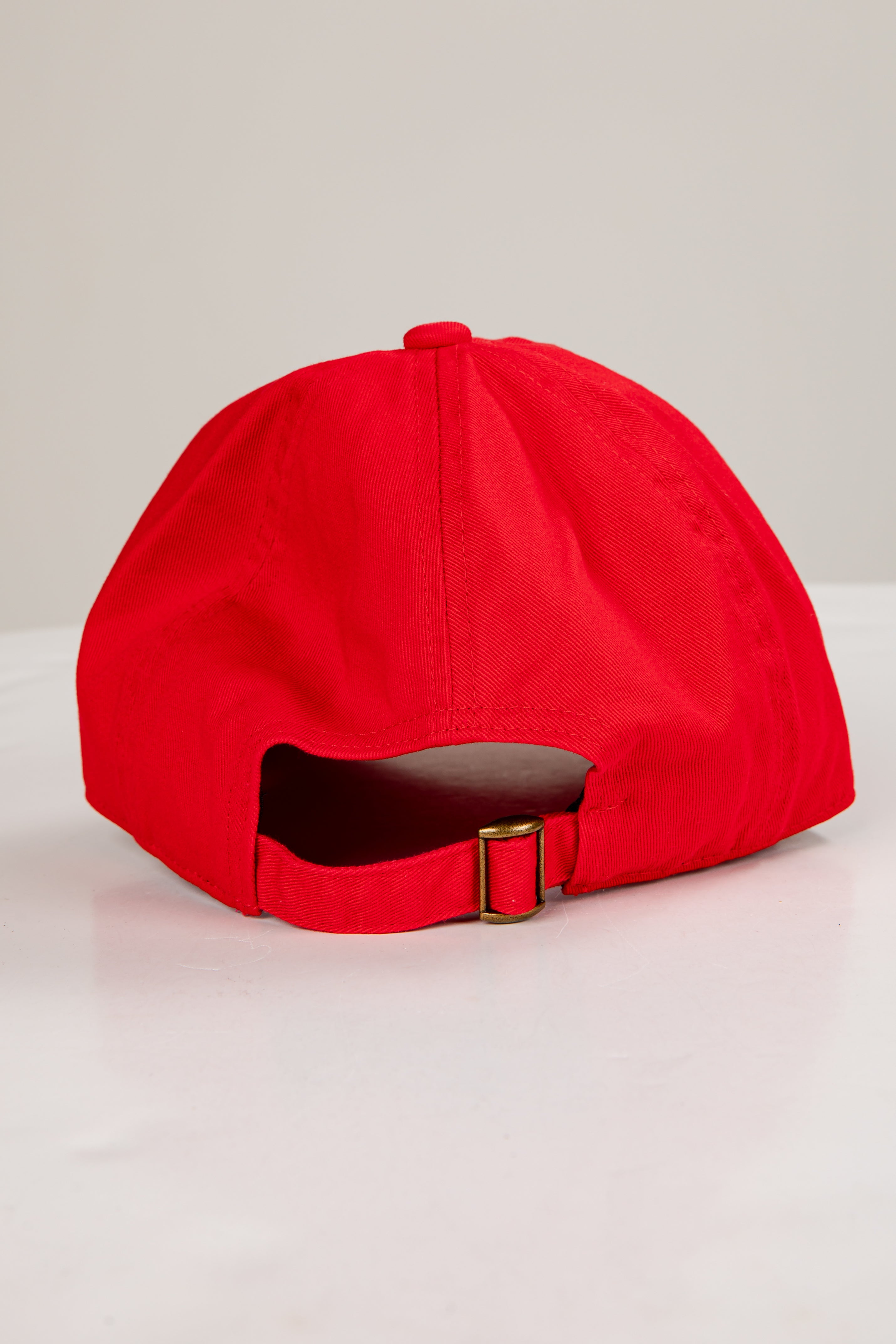Red cap with a gold buckle on a light gray background