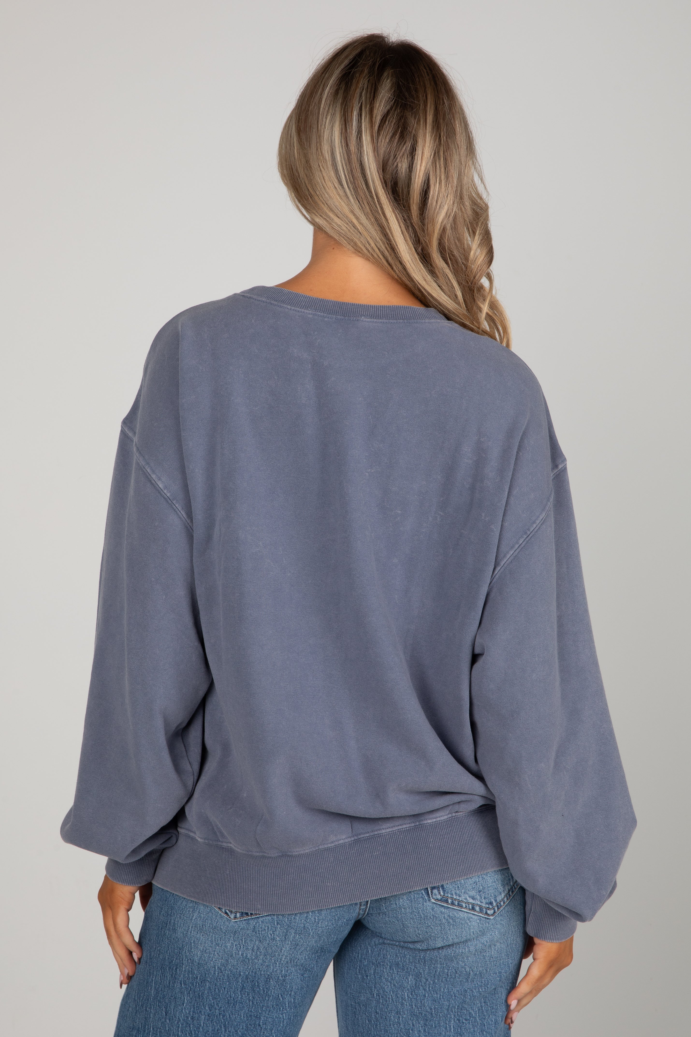 Person wearing a blue sweatshirt and jeans on a plain background