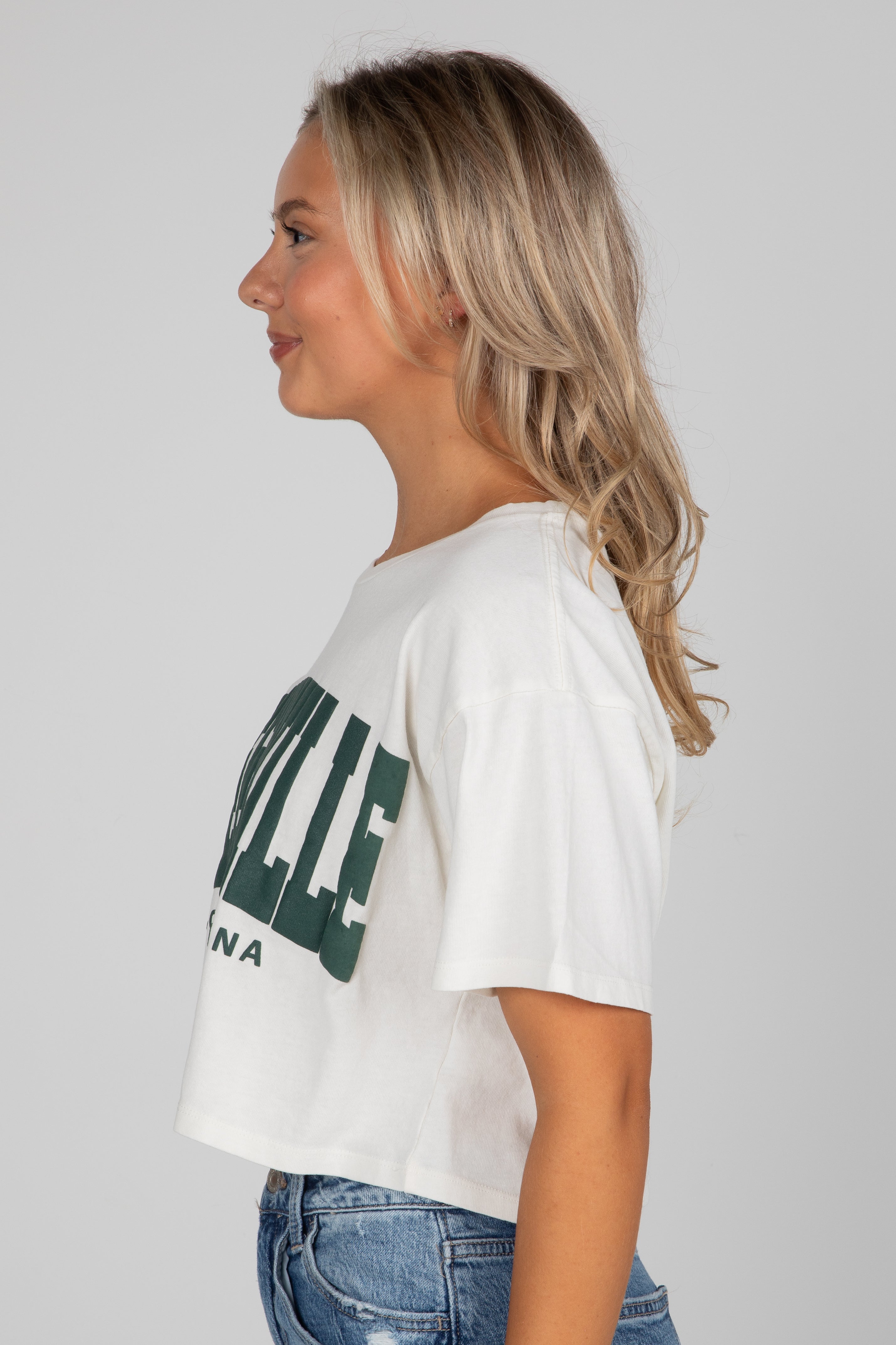 Woman wearing a white t-shirt with green text on a plain background