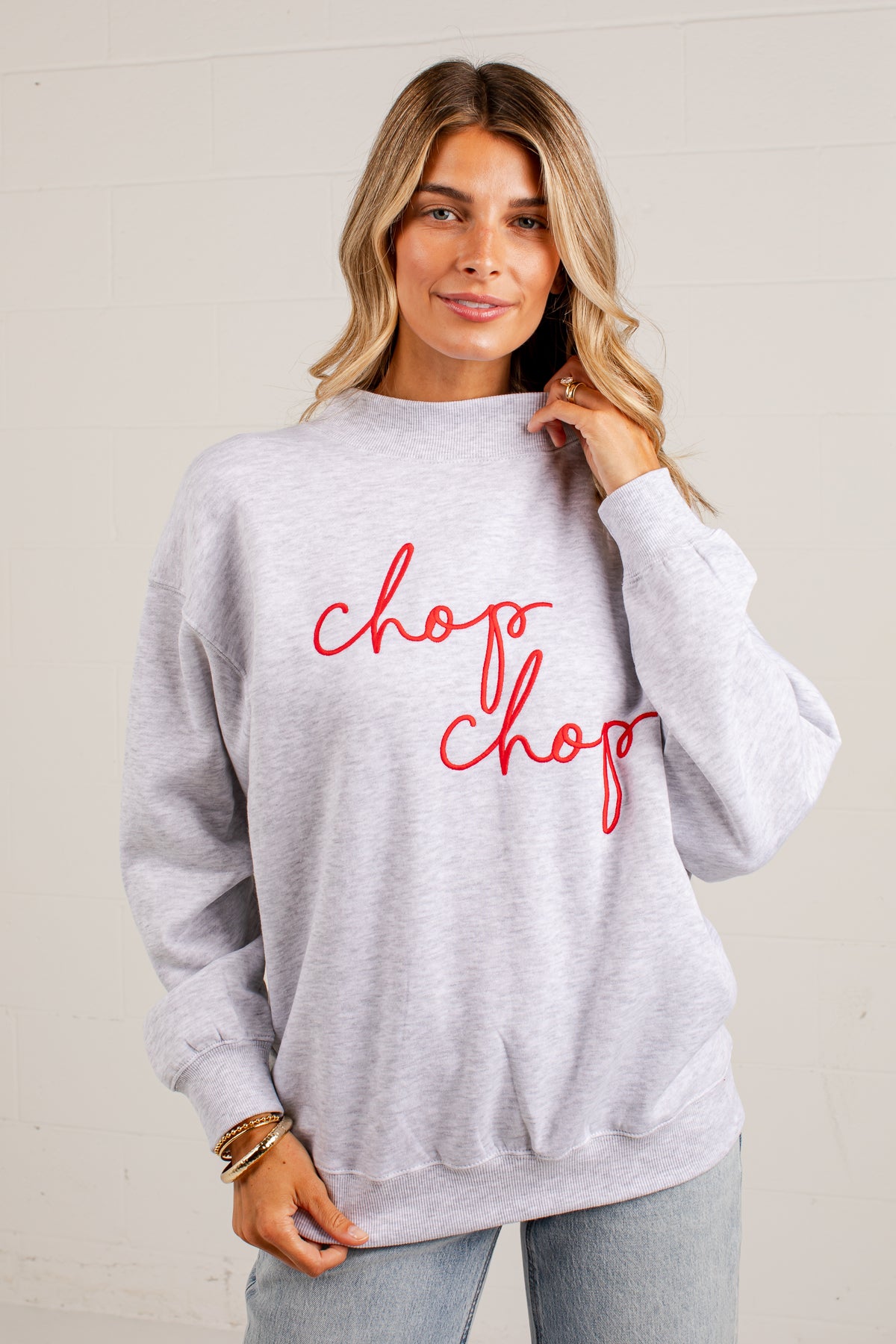 A woman wearing a light heather gray crewneck sweatshirt with &