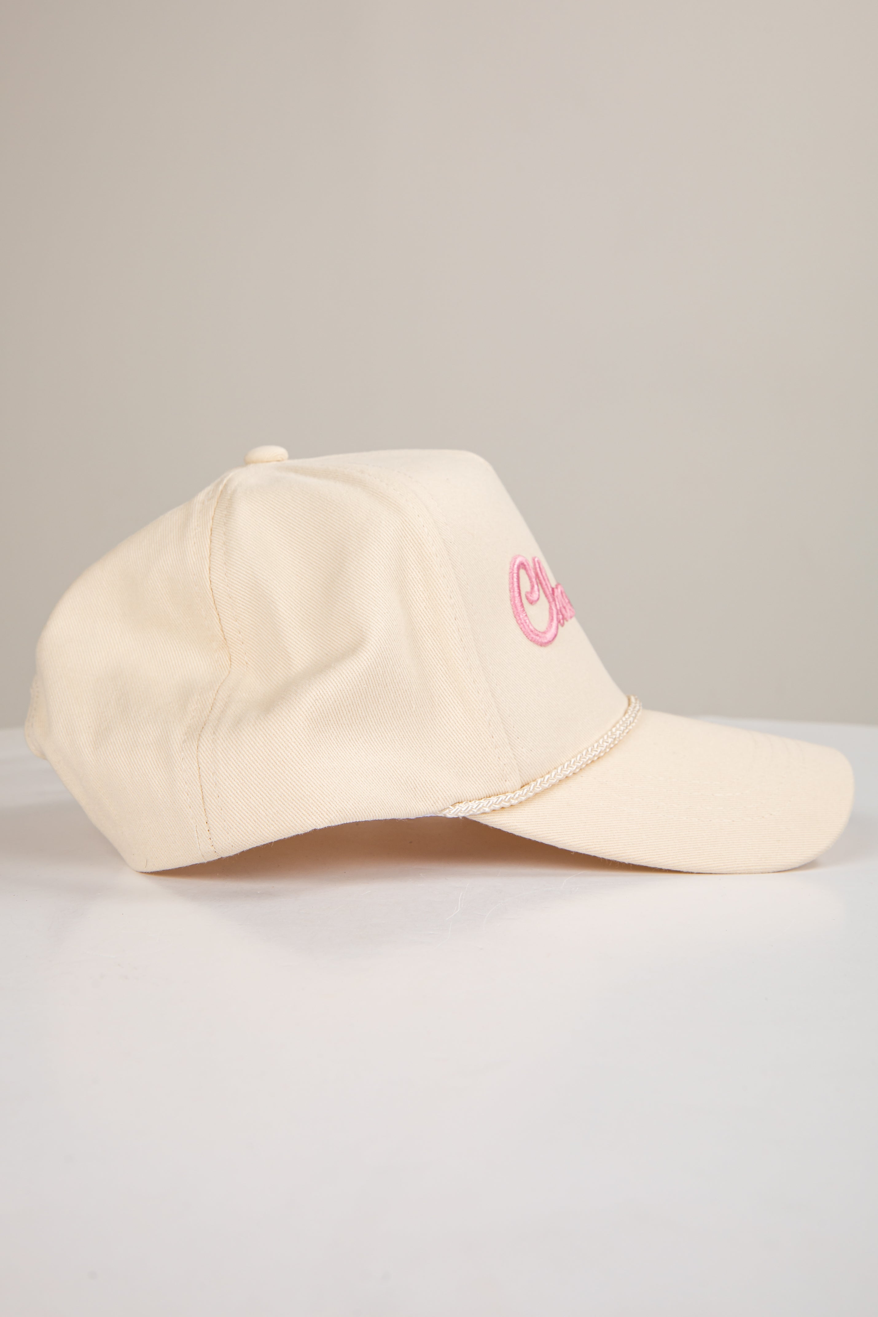 Beige cap with pink logo on a light gray background