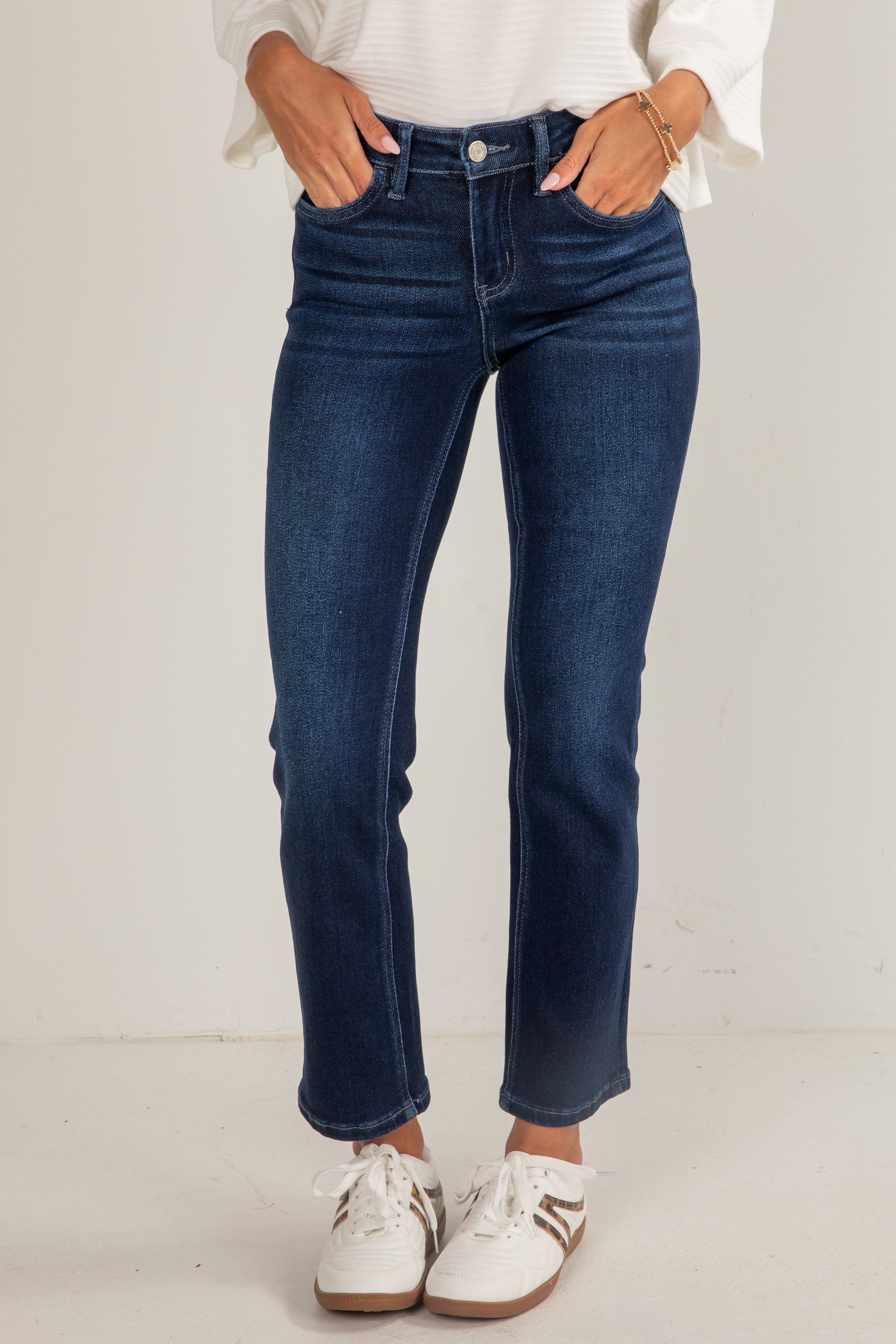 Person wearing blue jeans and white sneakers on a plain background