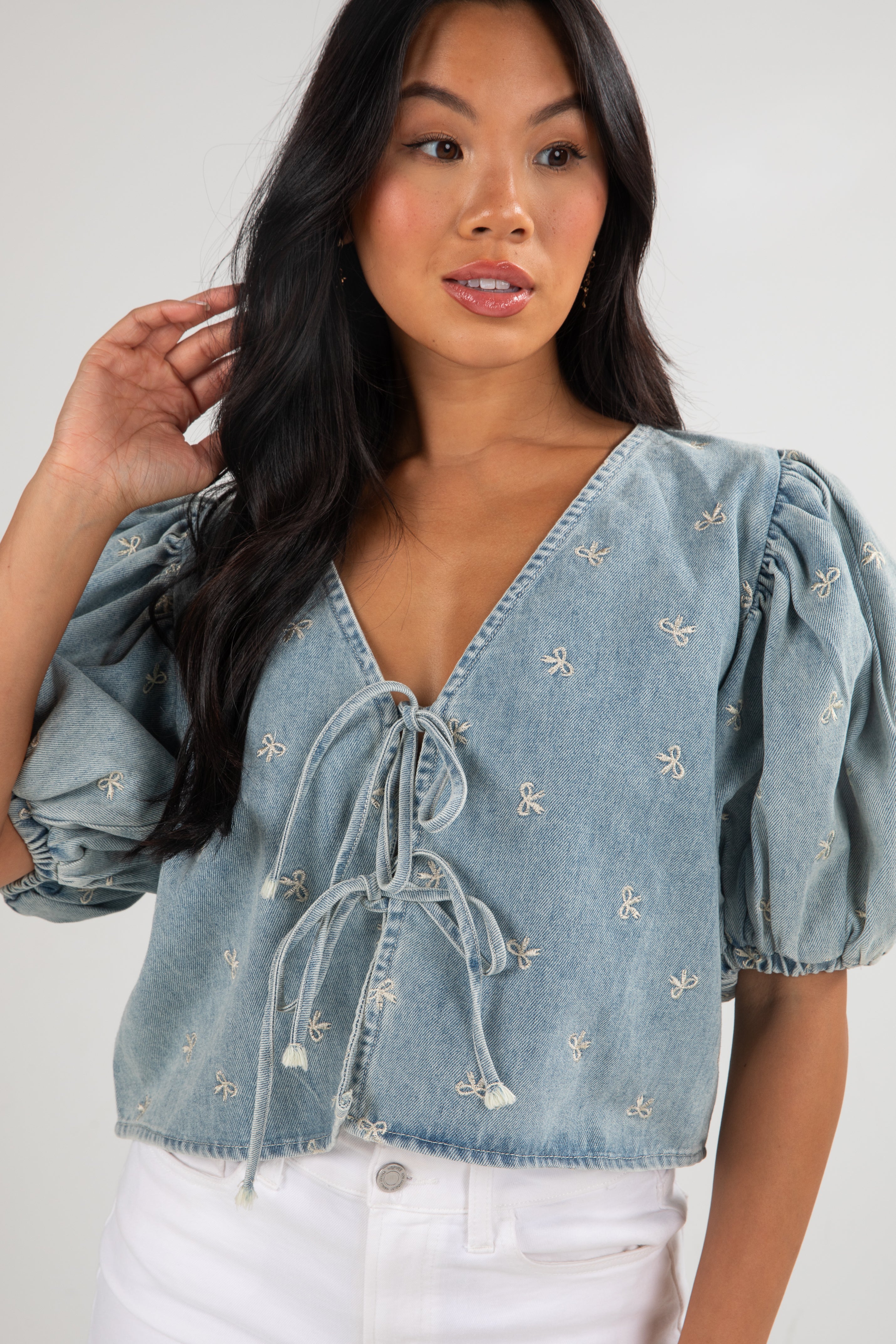 Woman wearing a light blue denim top with puff sleeves against a white background