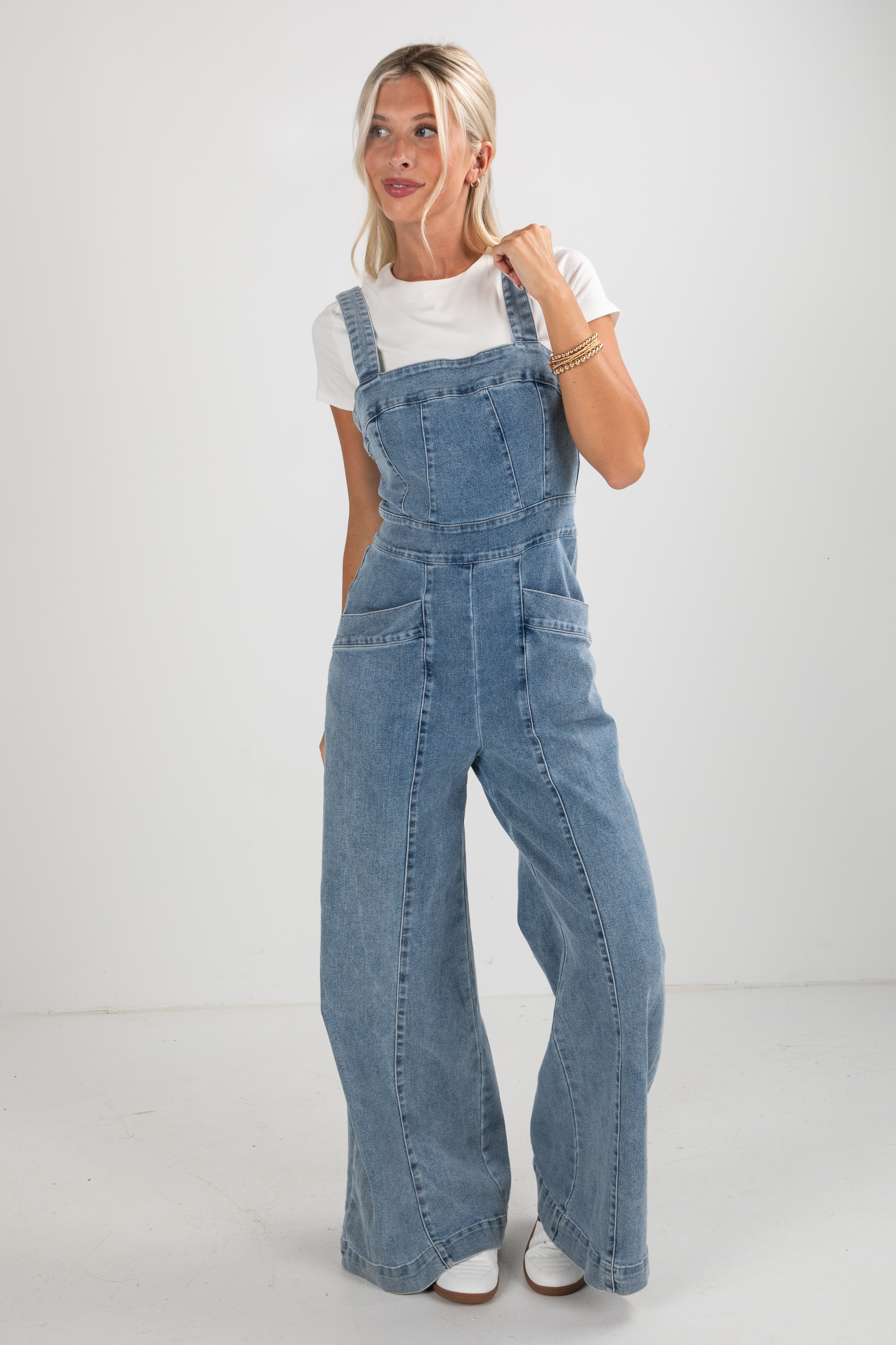 Woman wearing blue denim overalls on a white background