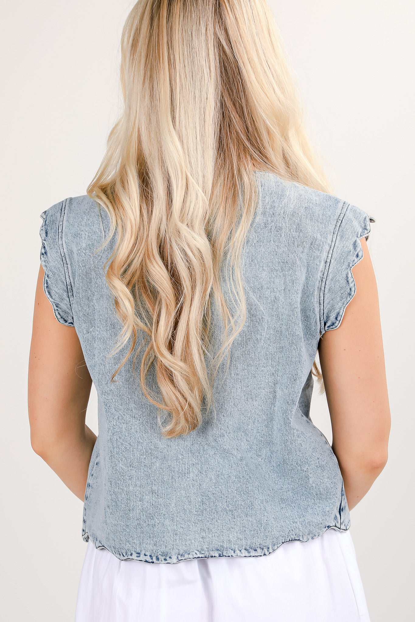 Light blue denim top worn by a person with long blonde hair on a plain background