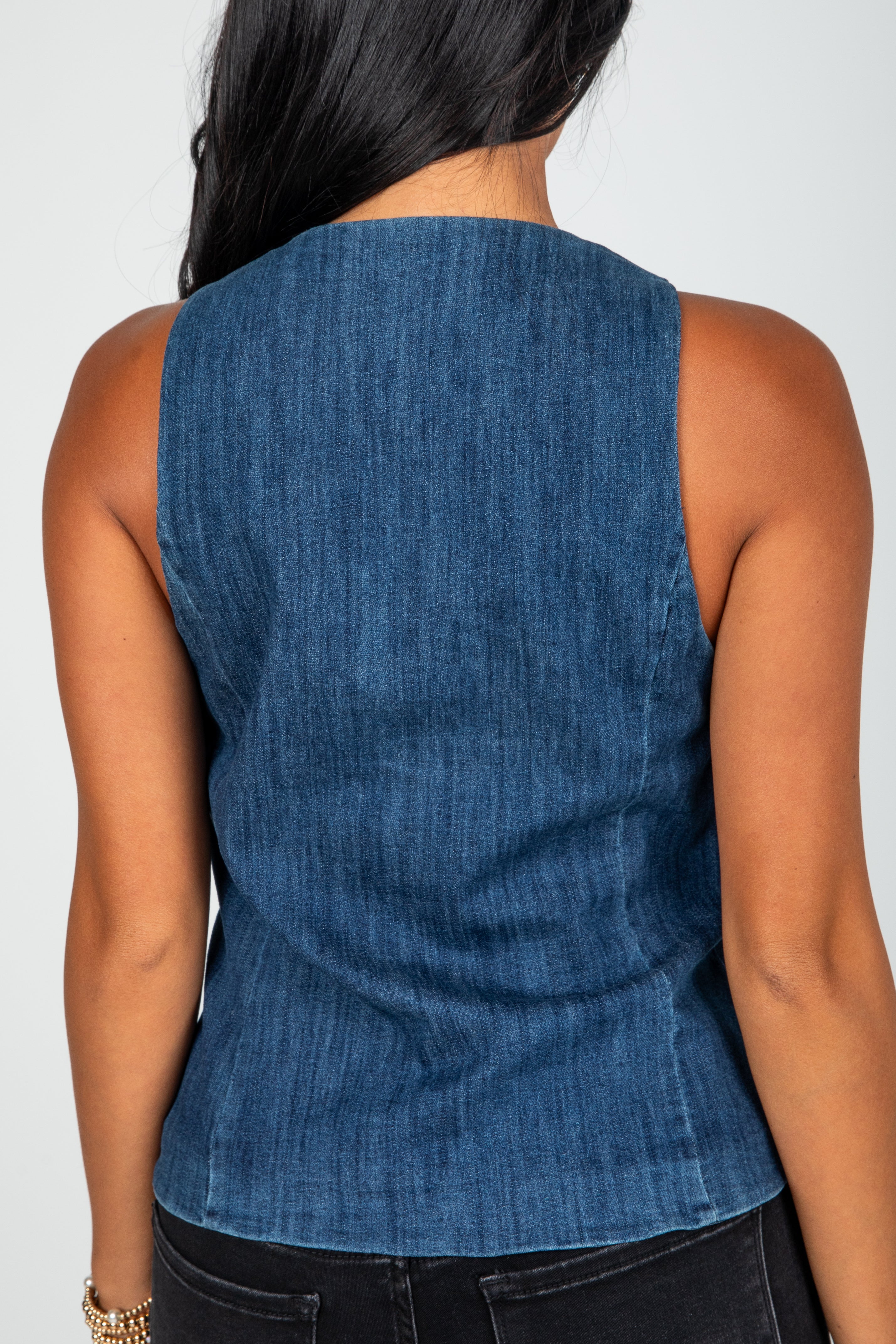 Blue denim sleeveless top worn by a person on a white background