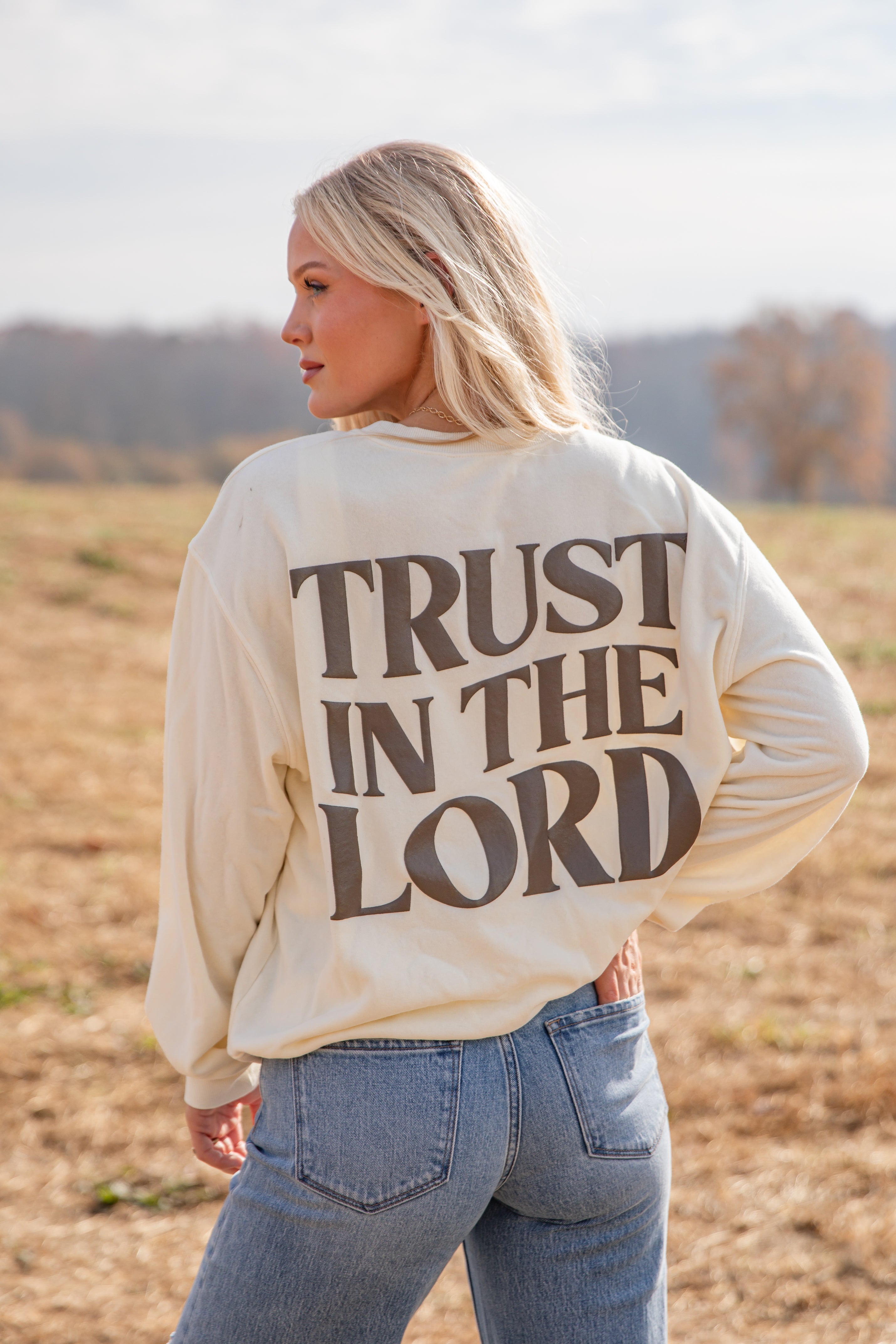 Woman wearing a cream sweatshirt with &