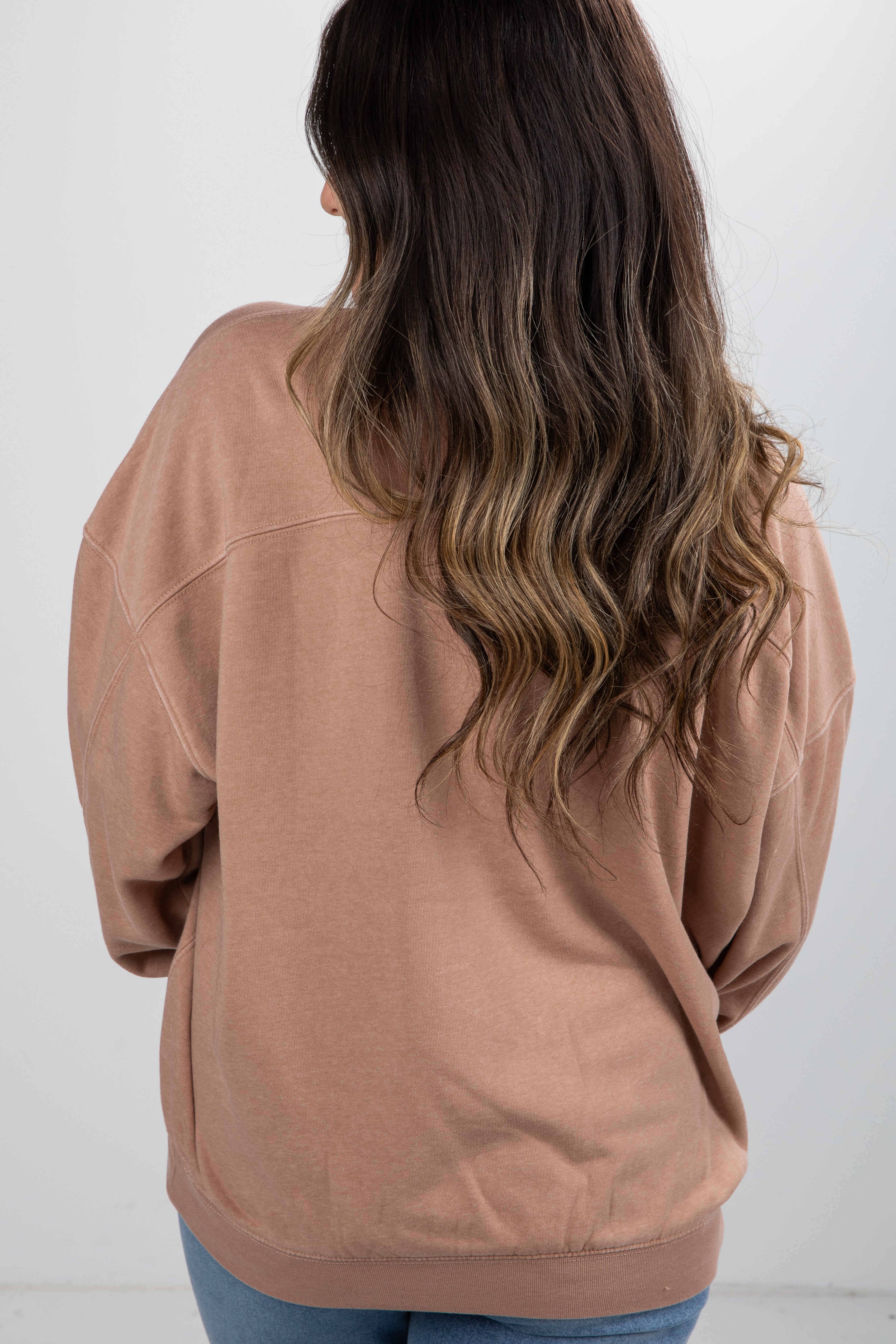 Person wearing a brown sweatshirt with a plain white background