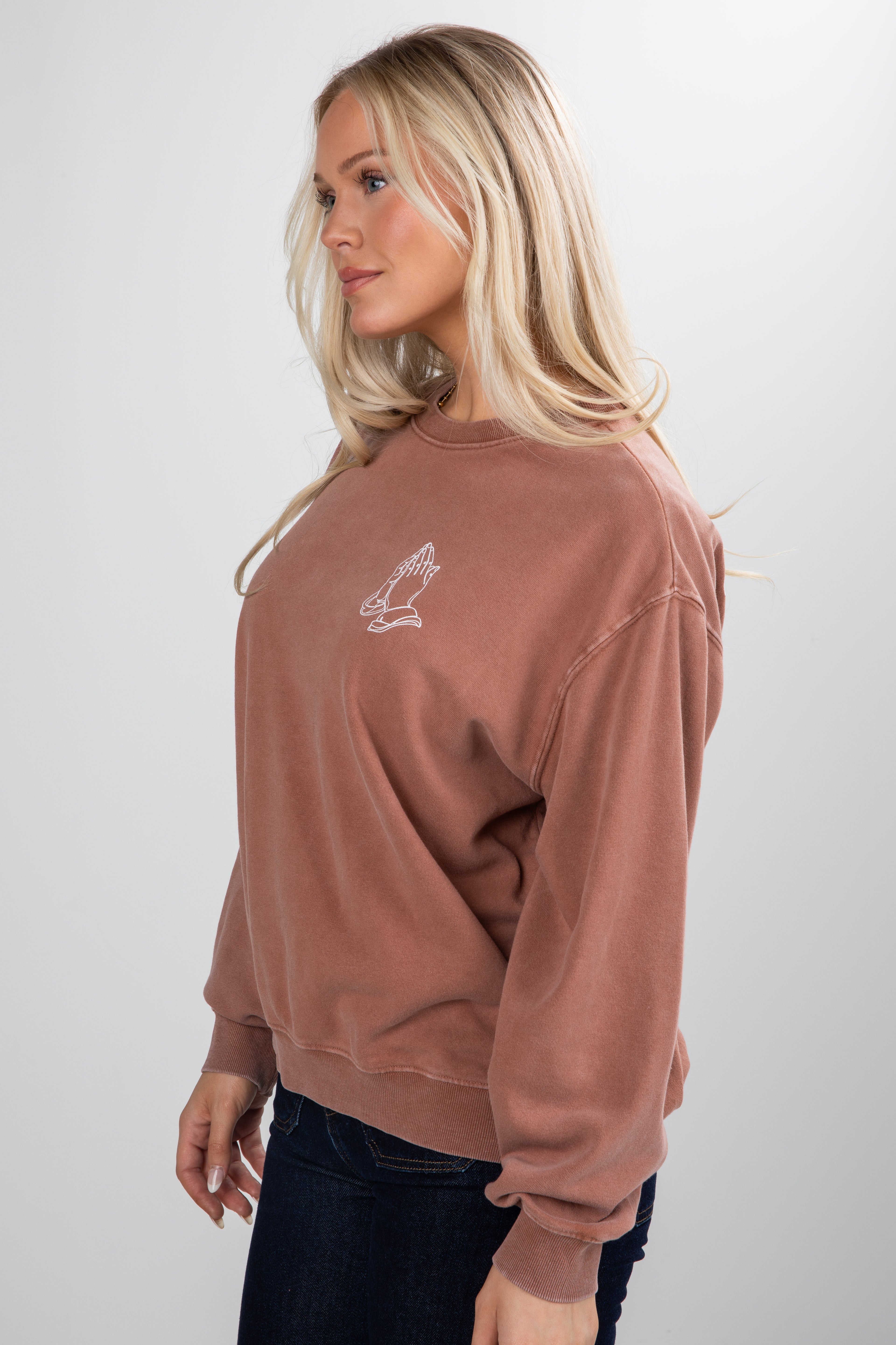 Woman wearing a brown sweatshirt with a logo on a white background