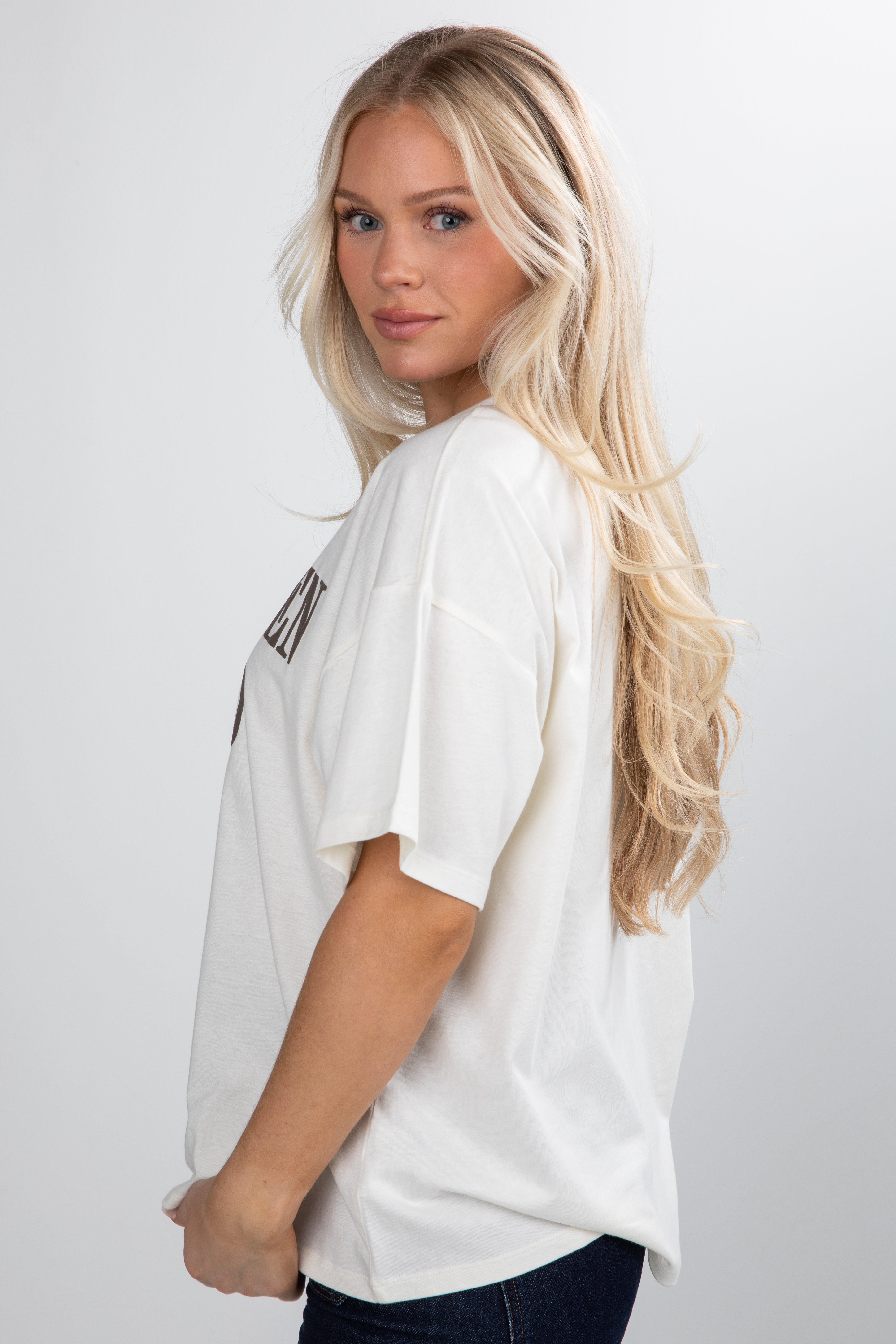Woman wearing a white oversized t-shirt with text on a plain background