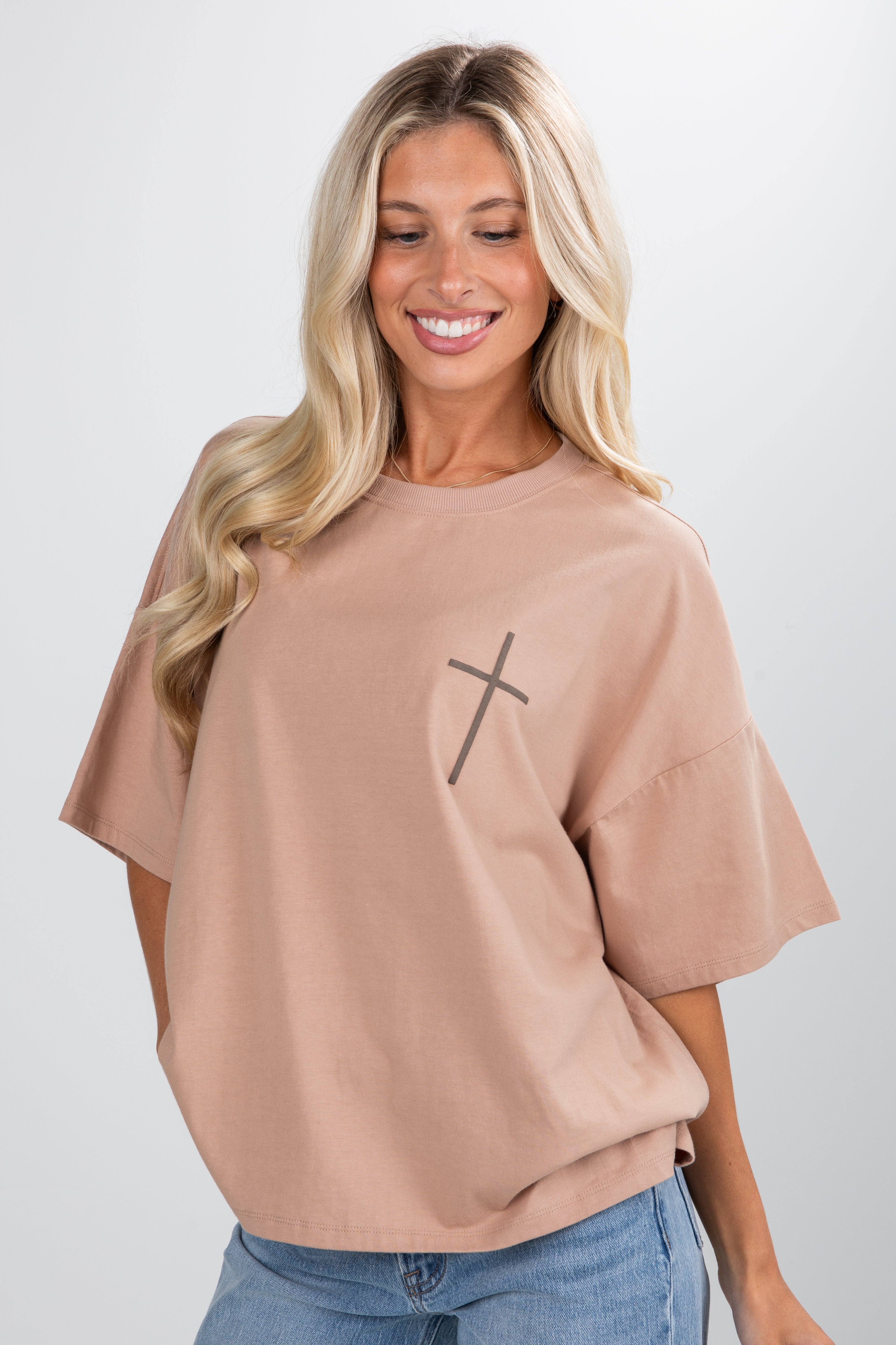 Woman wearing a beige t-shirt with a black cross design on a white background