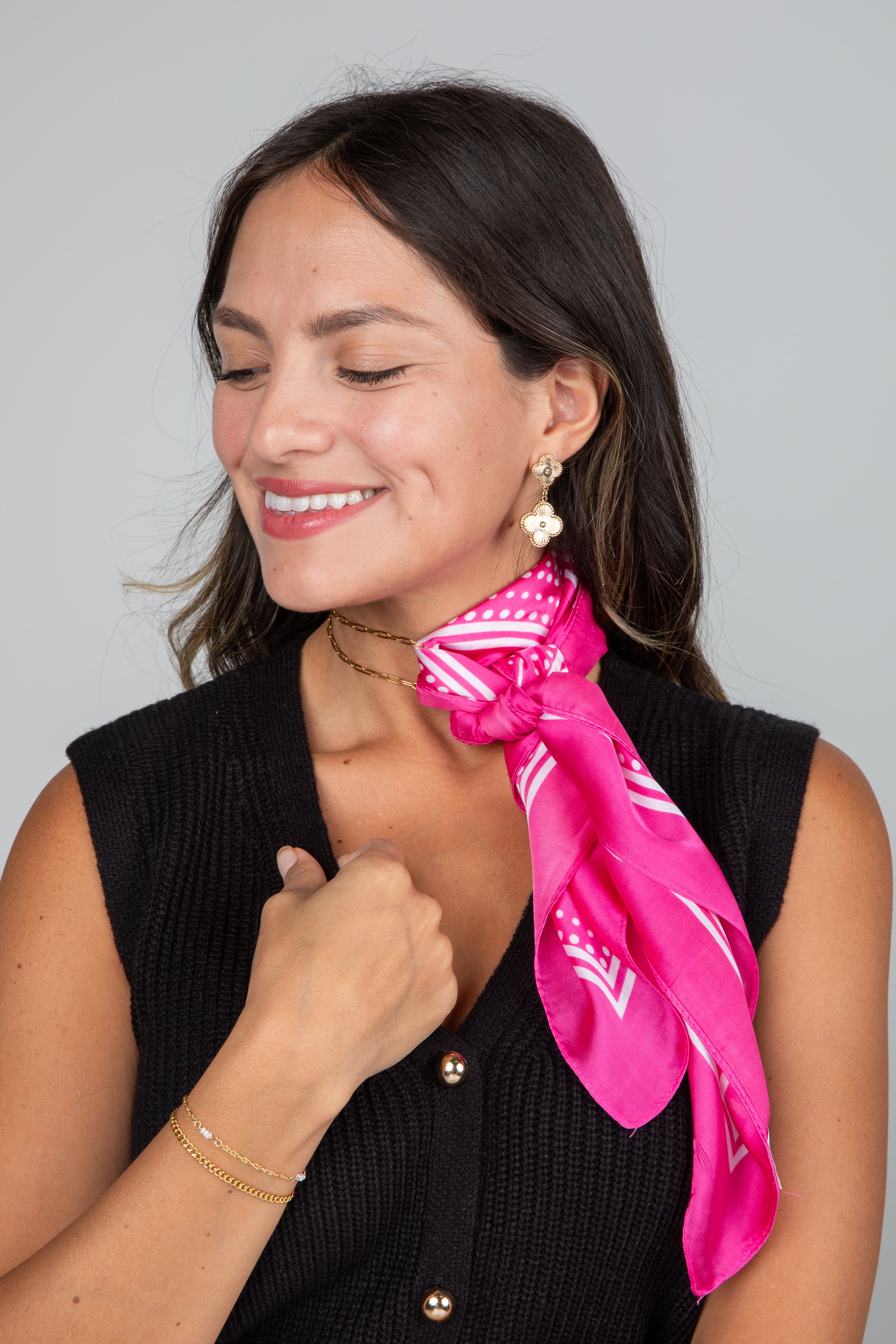 Woman wearing a pink scarf with white patterns on a gray background
