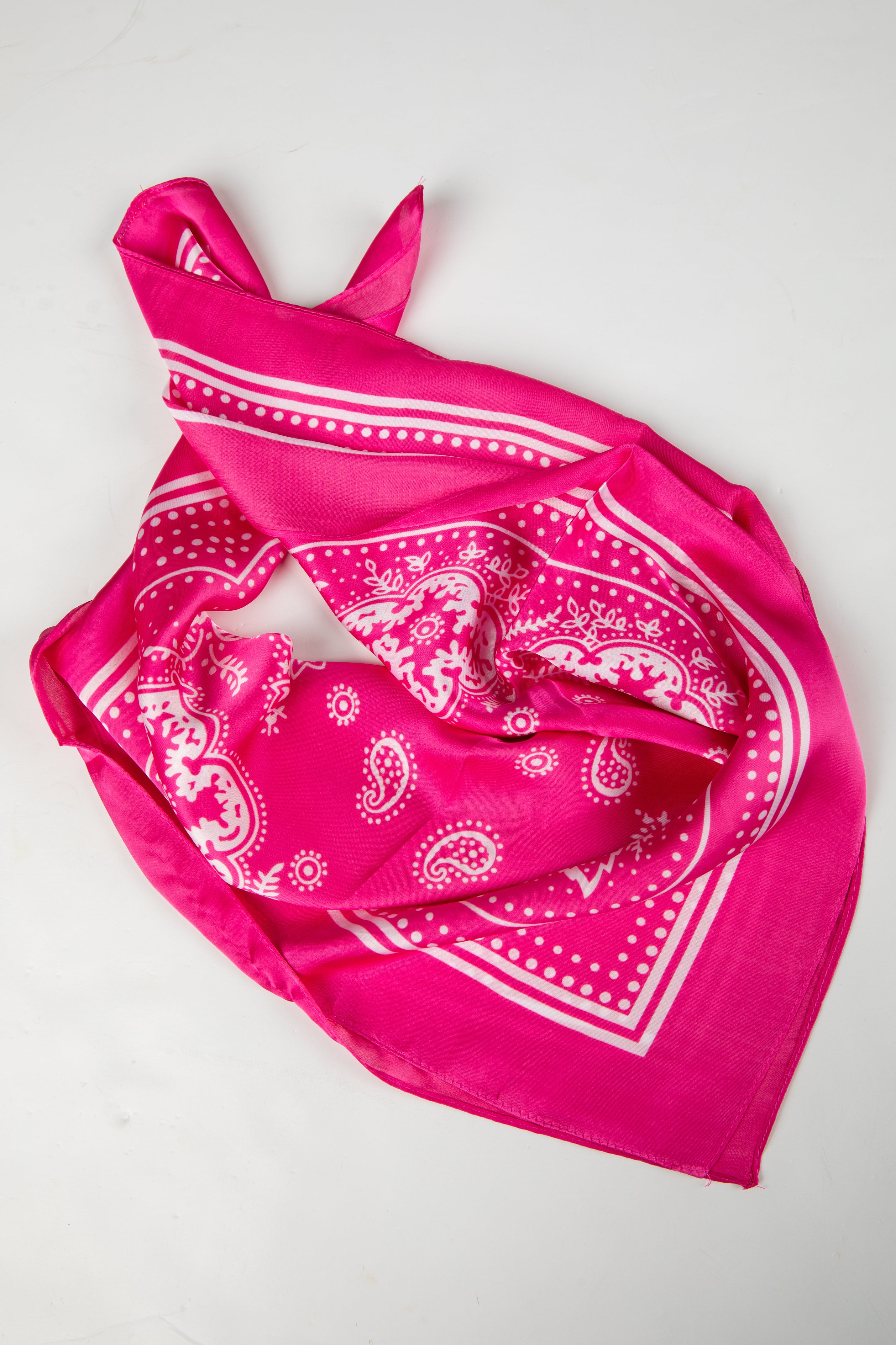 Pink bandana with white paisley pattern on a light gray background