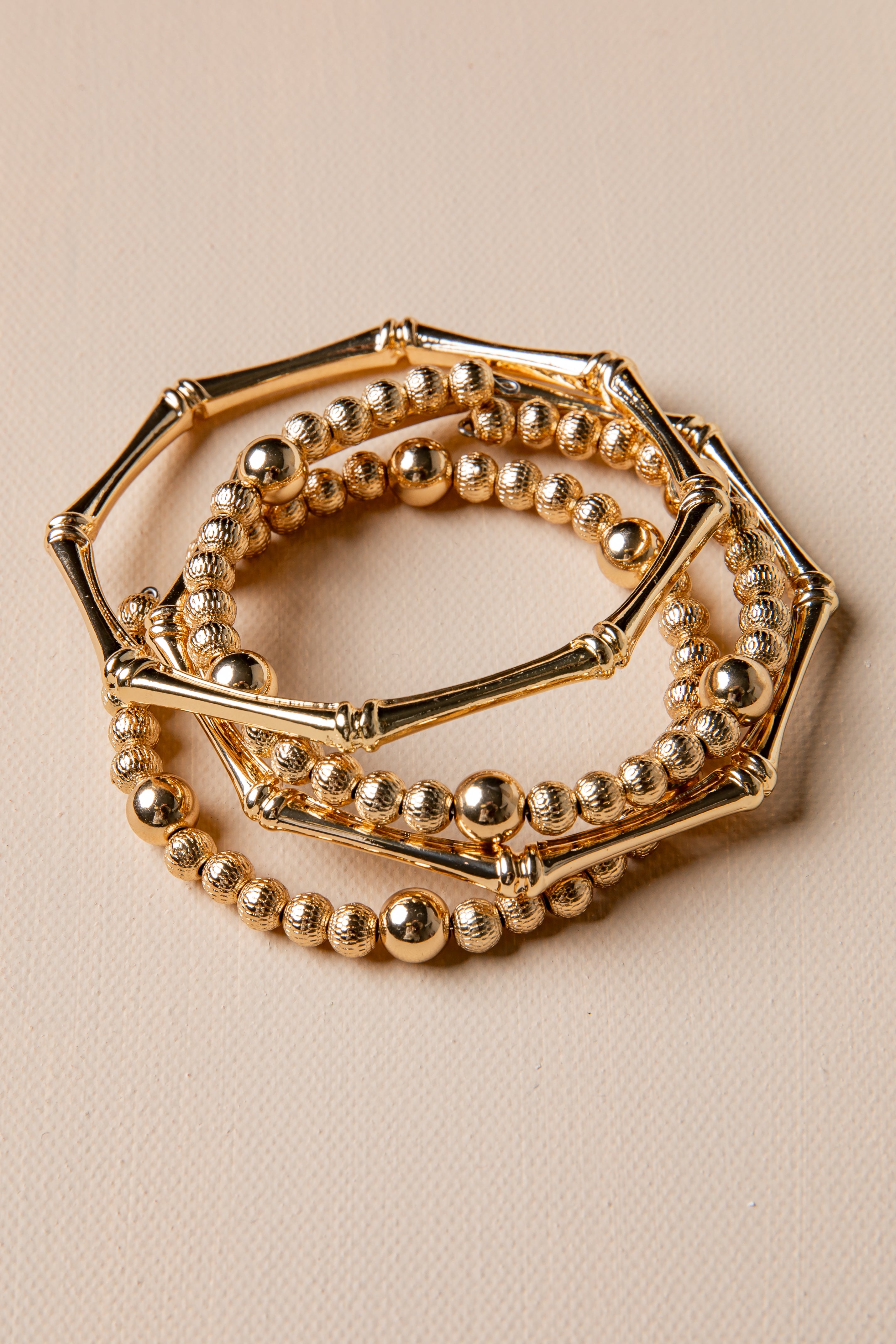 Set of gold beaded bracelets on a beige background