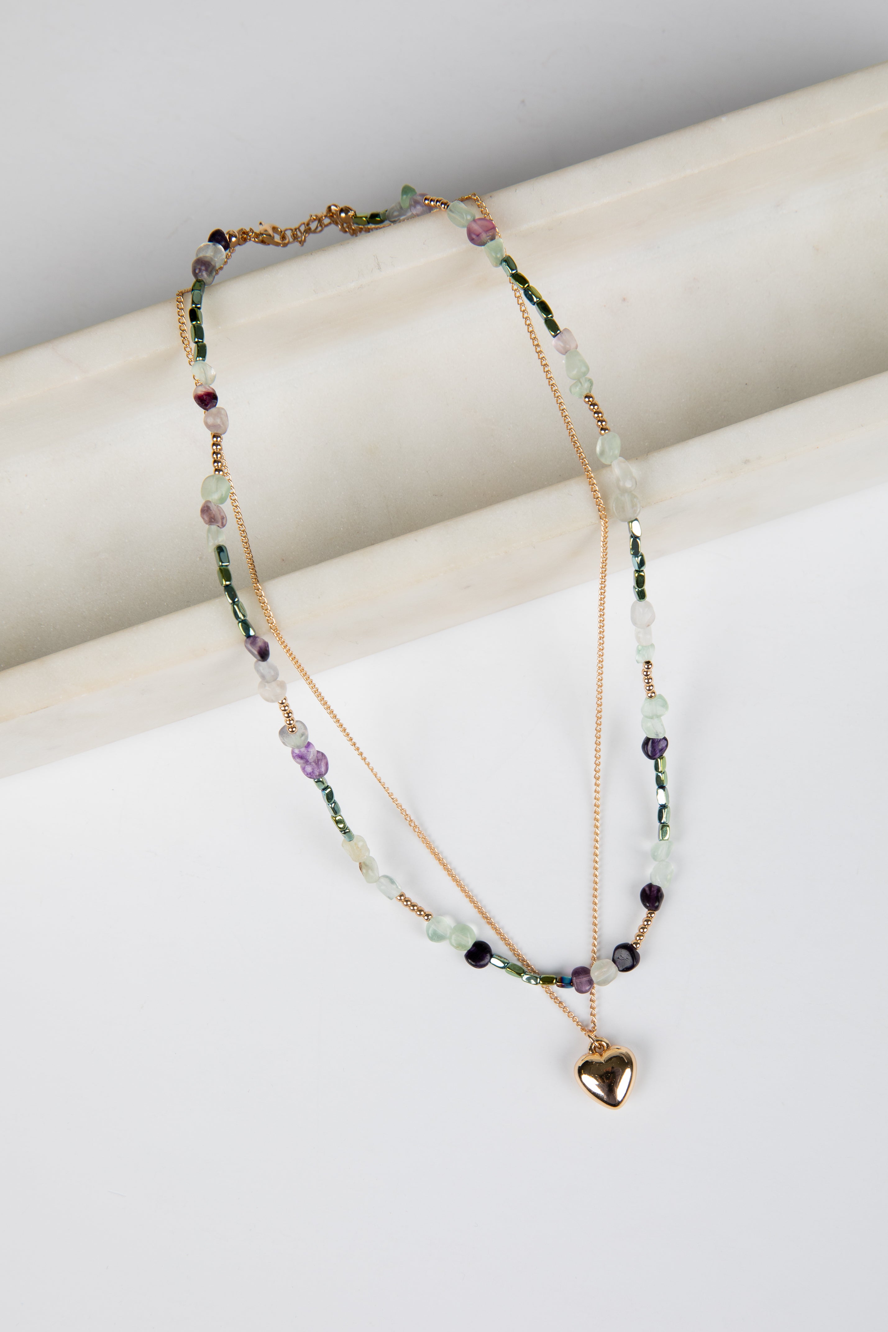 Multicolored beaded necklace with a heart pendant on a white surface