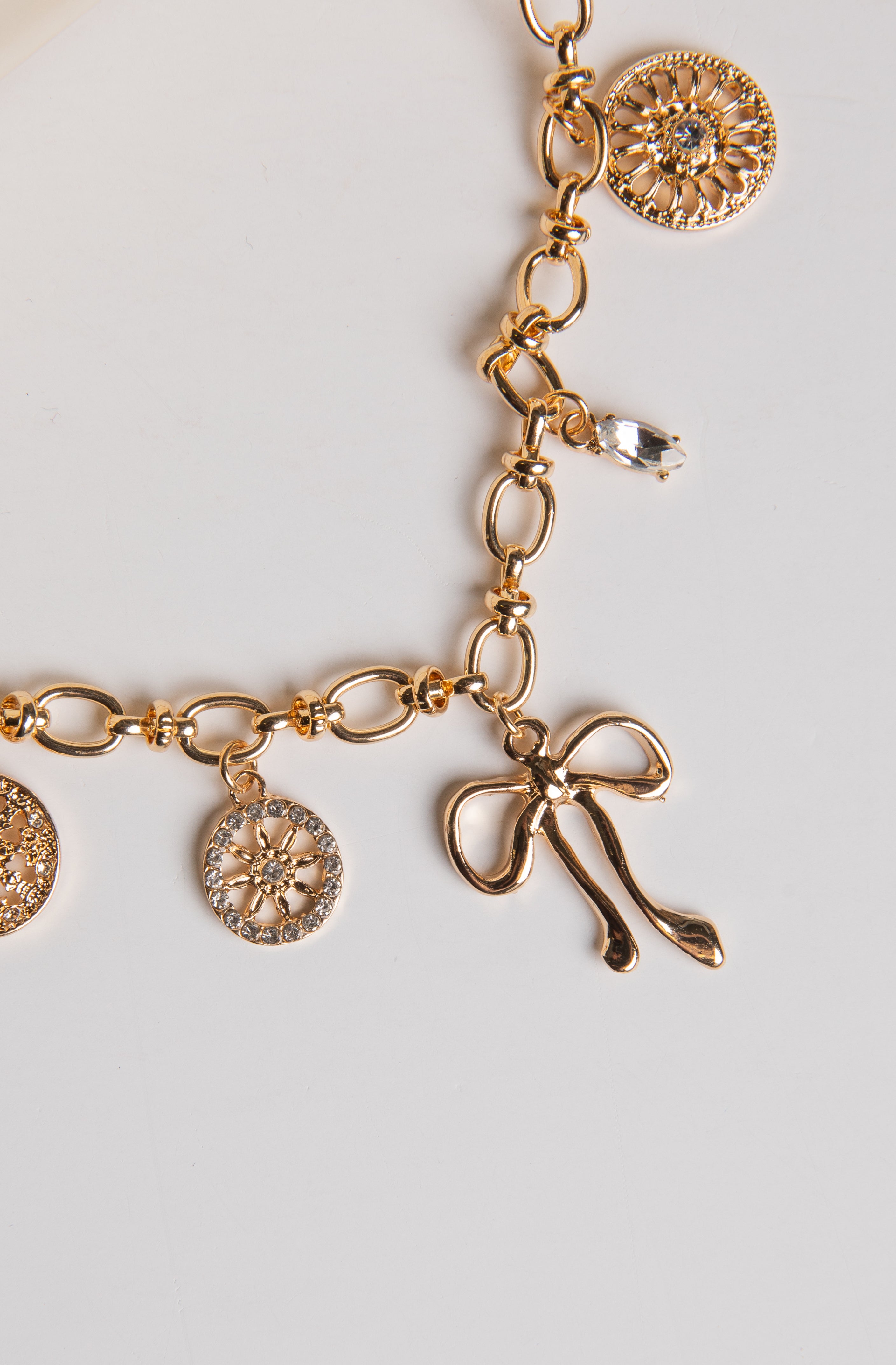 Gold bracelet with various charms on a light gray background