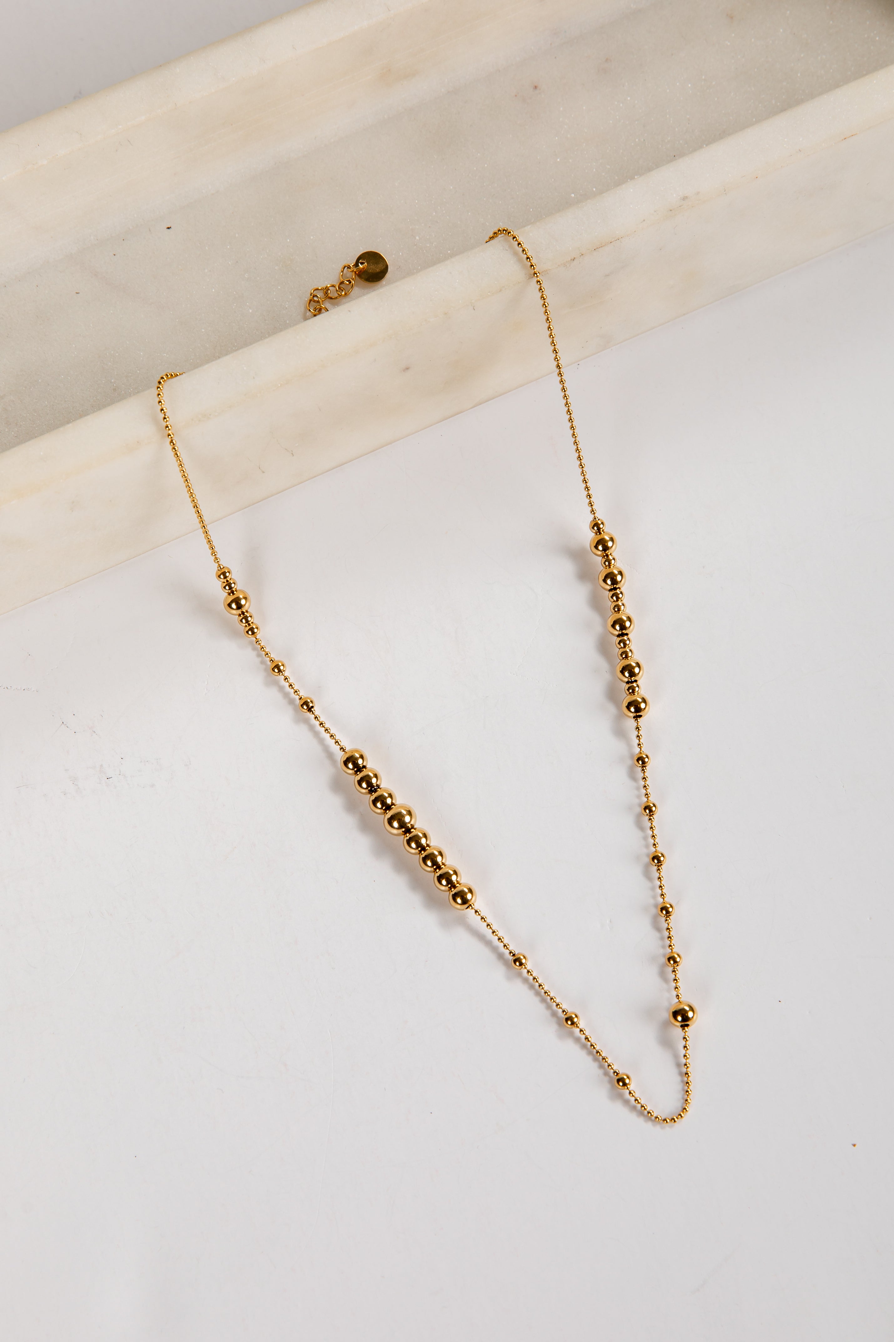 Gold beaded necklace on a white surface