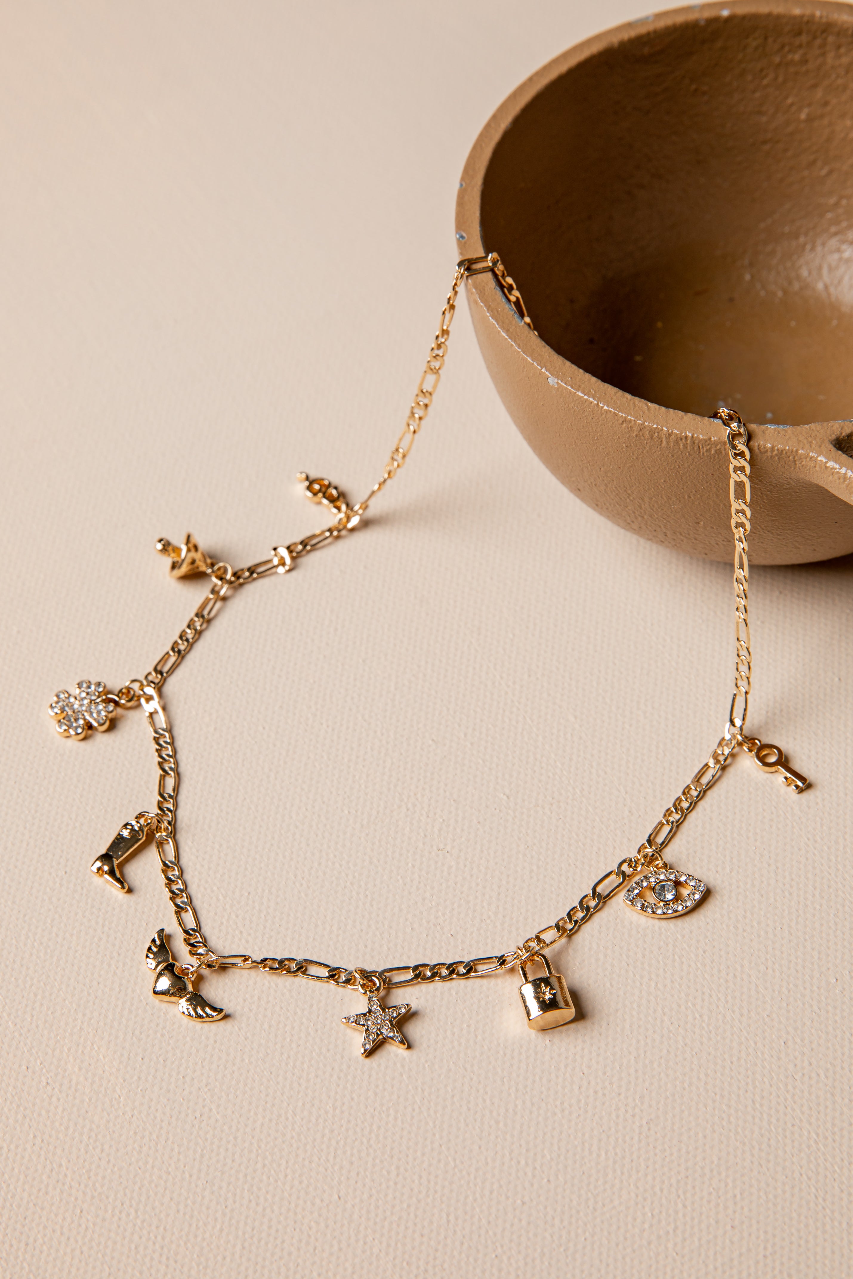 Gold bracelet with charms on a beige surface