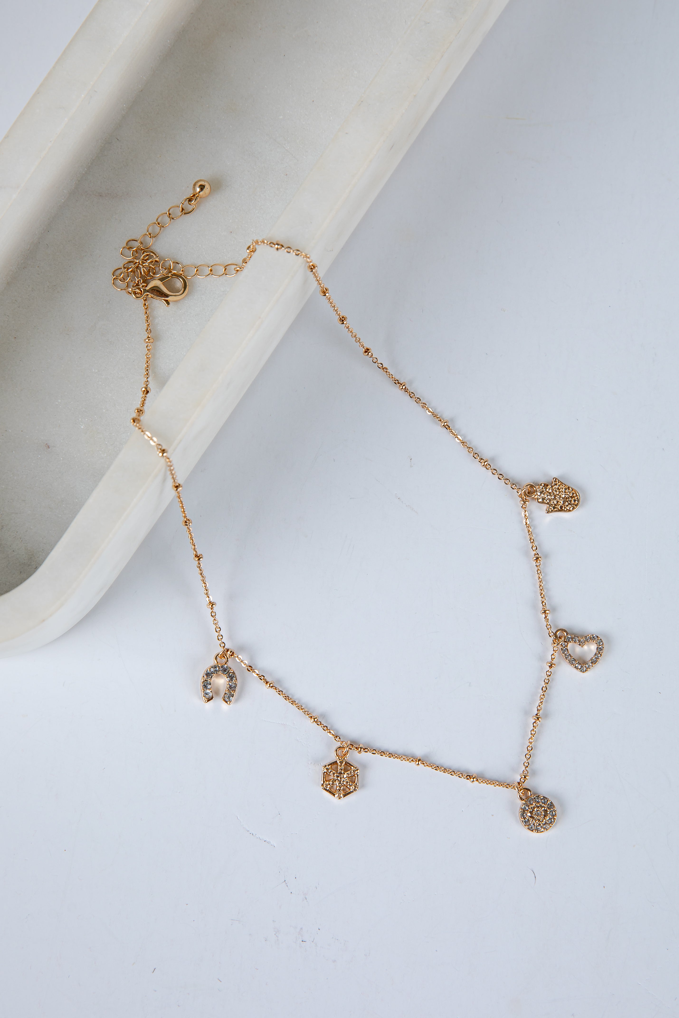 Gold bracelet with heart-shaped charms on a white surface