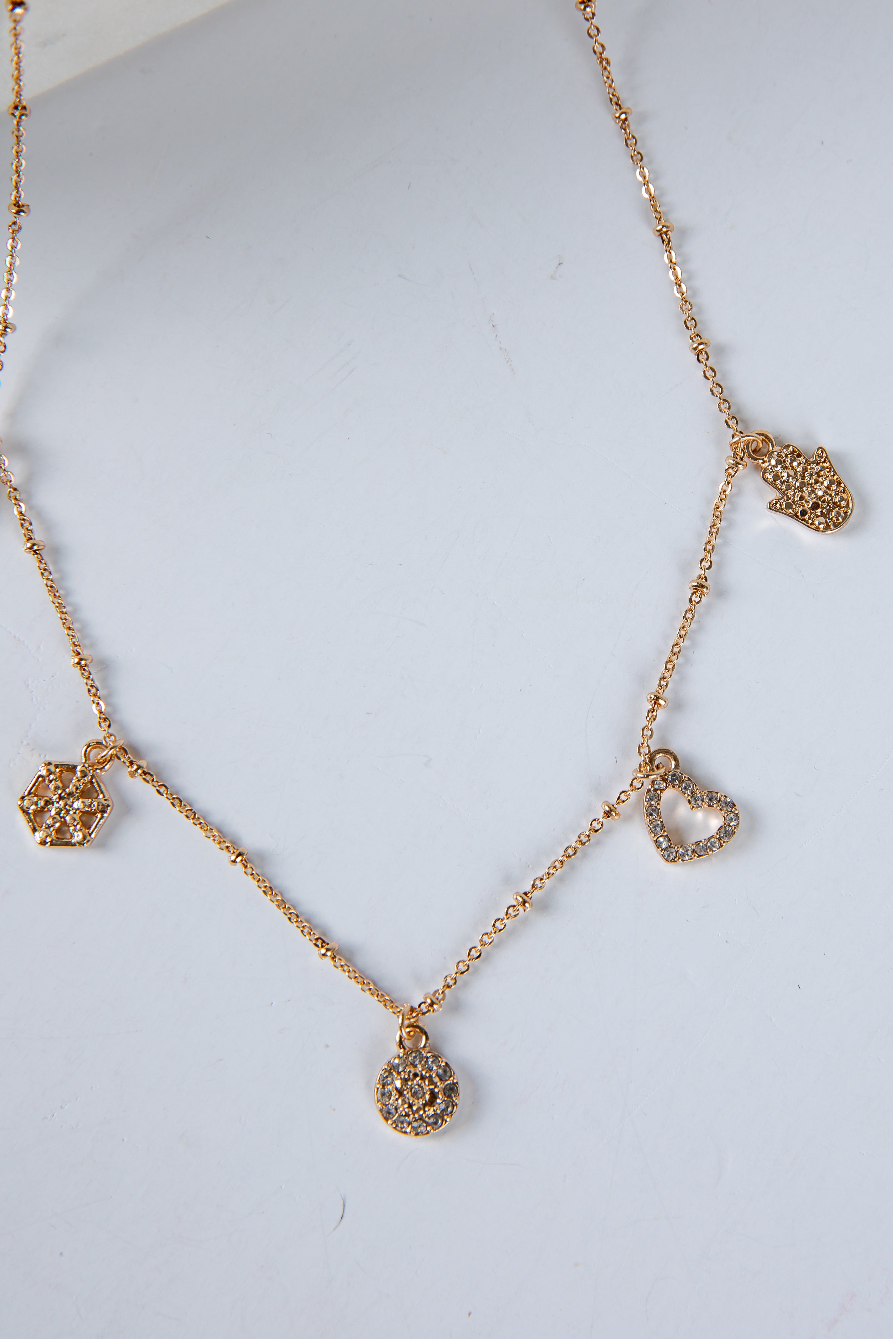 Gold necklace with heart-shaped pendants on a light gray background