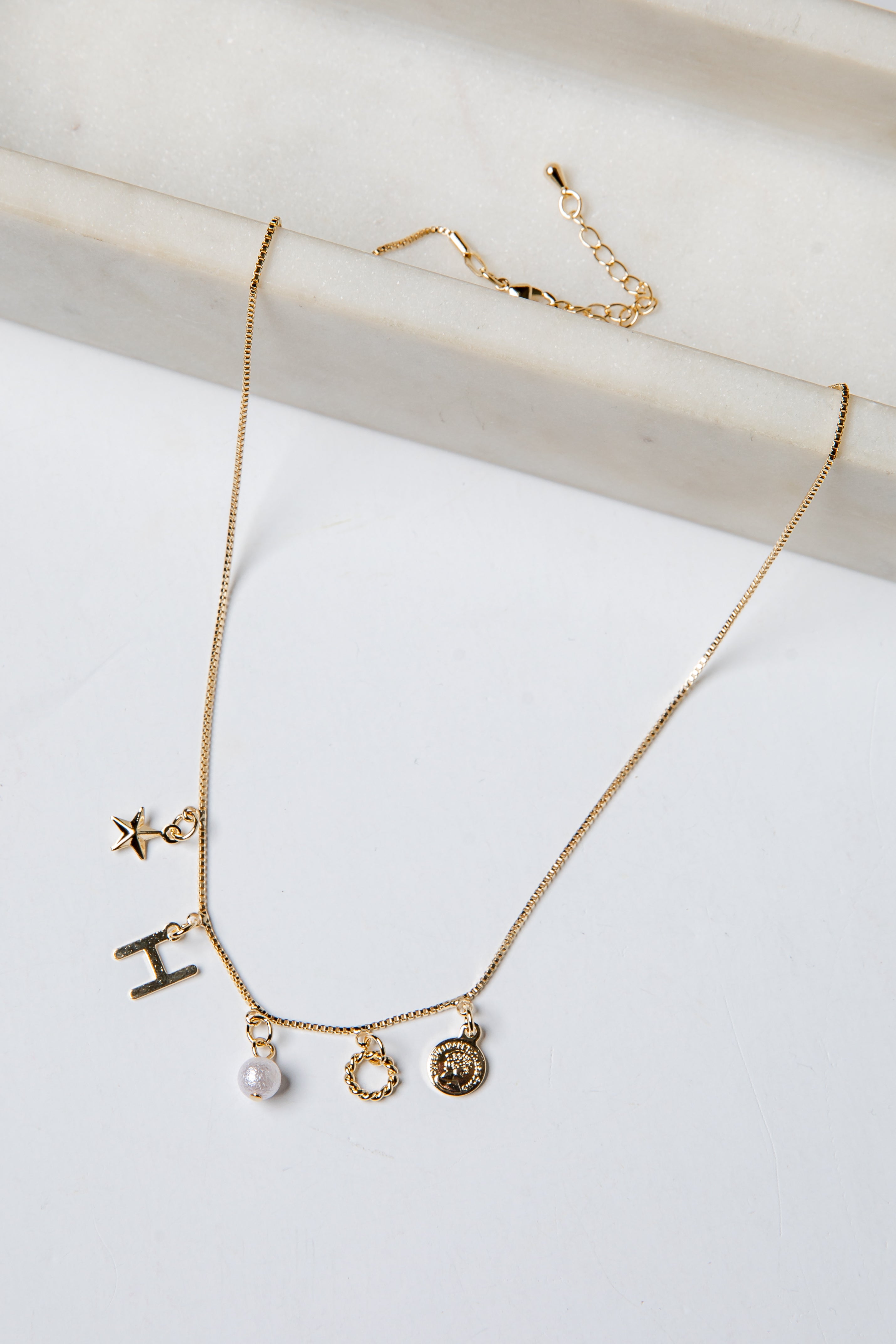 Gold necklace with various charms on a white background