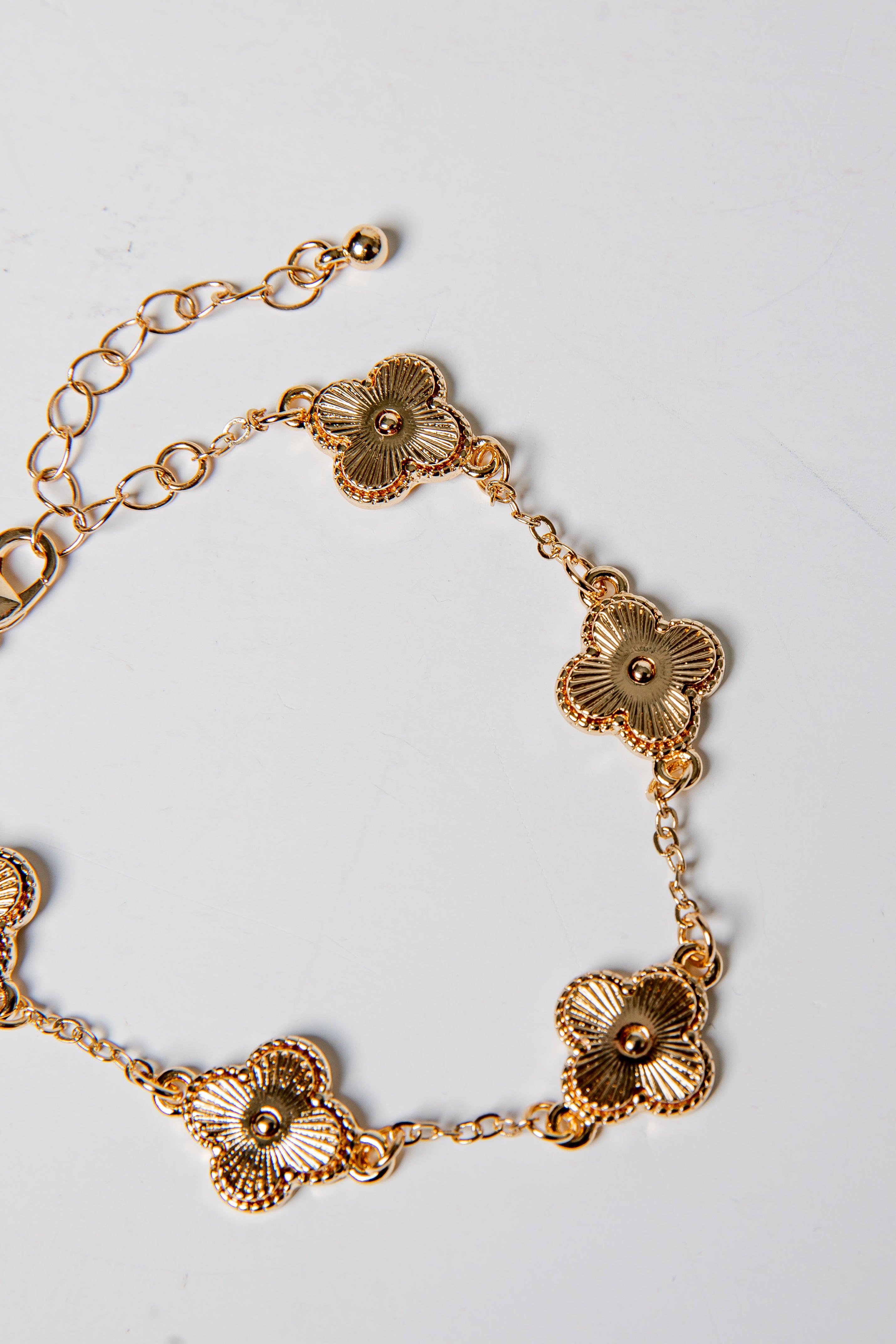 Gold bracelet with floral designs on a light gray background