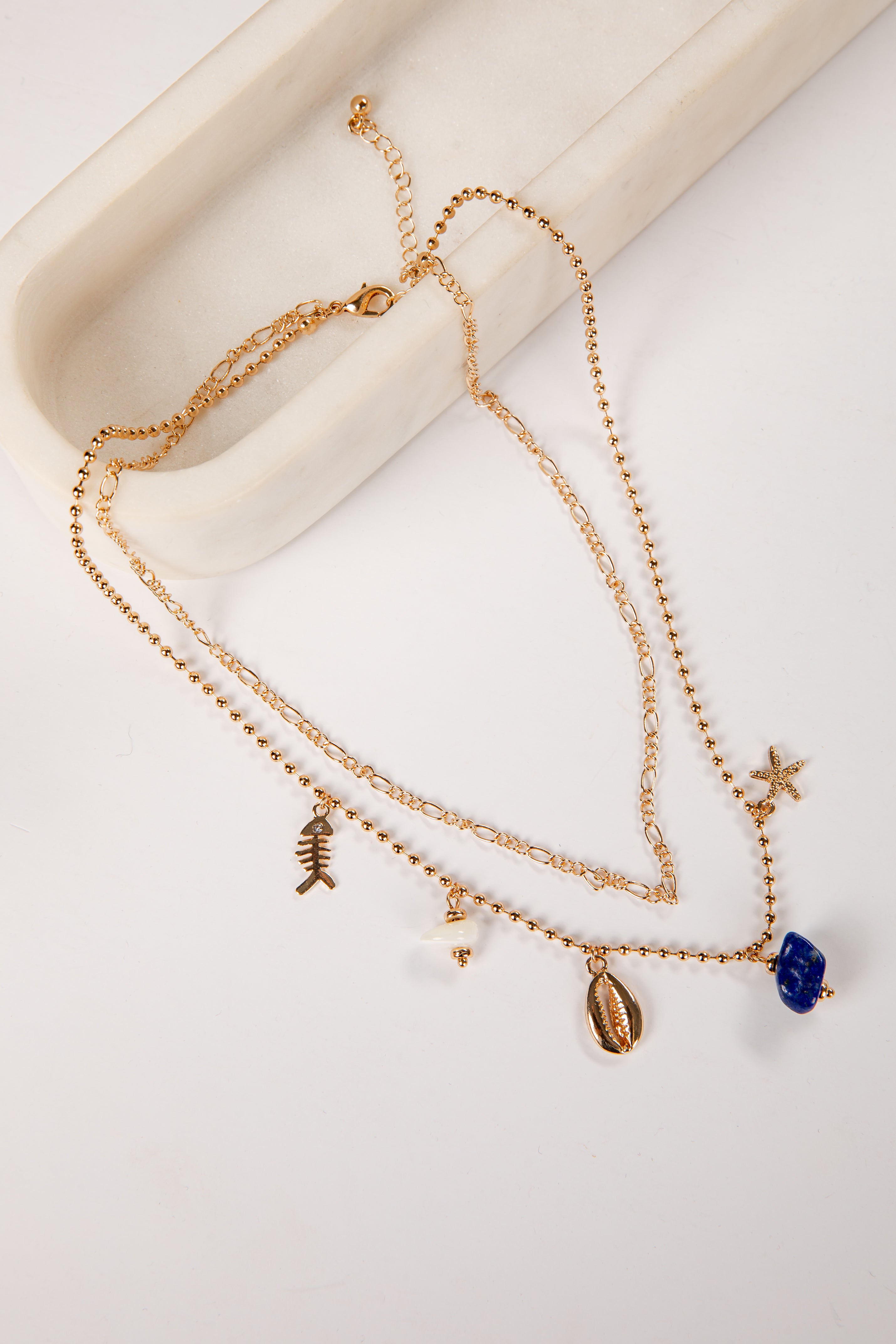 Gold necklace with charms on a white surface