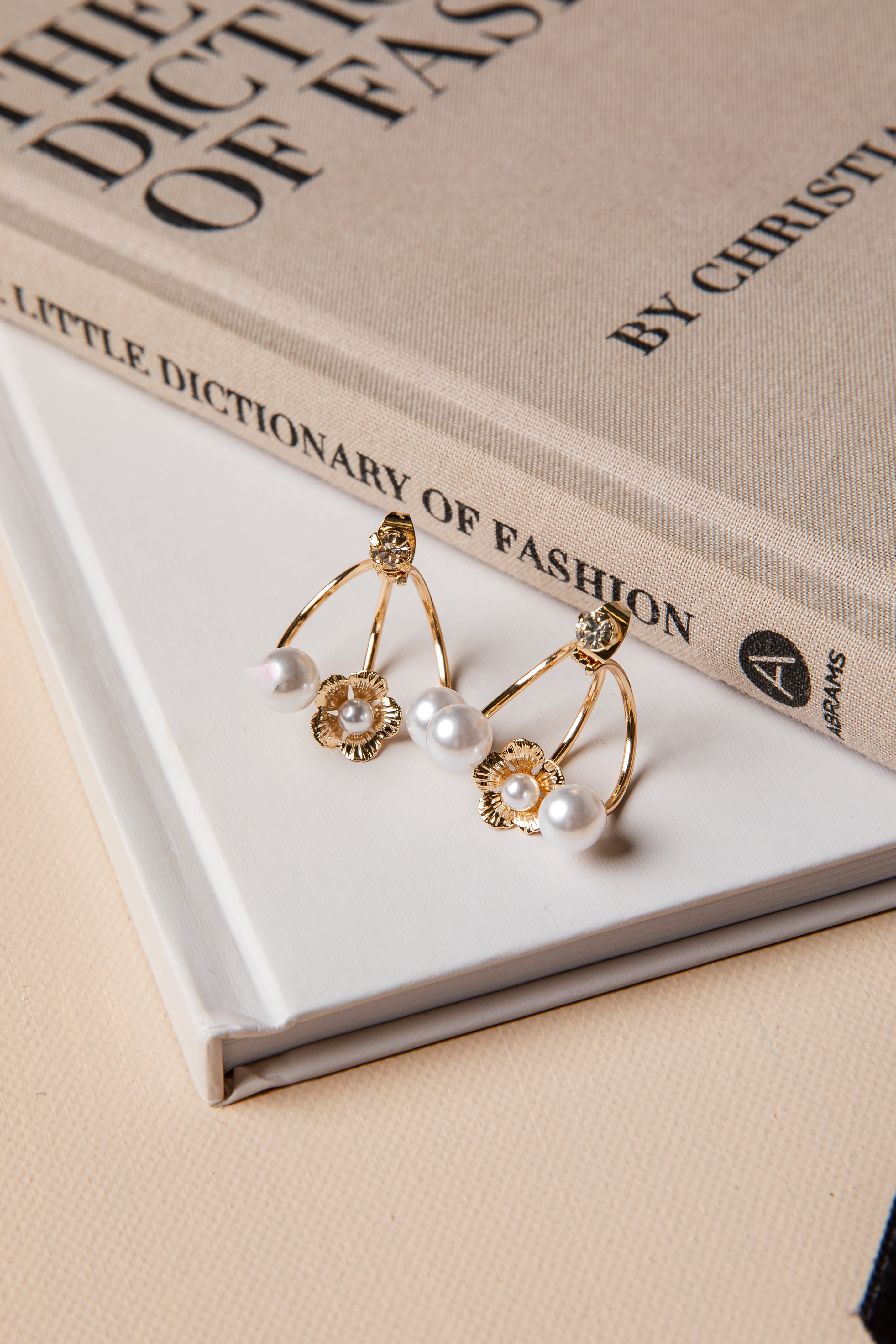 Gold earrings with pearls on a book titled &