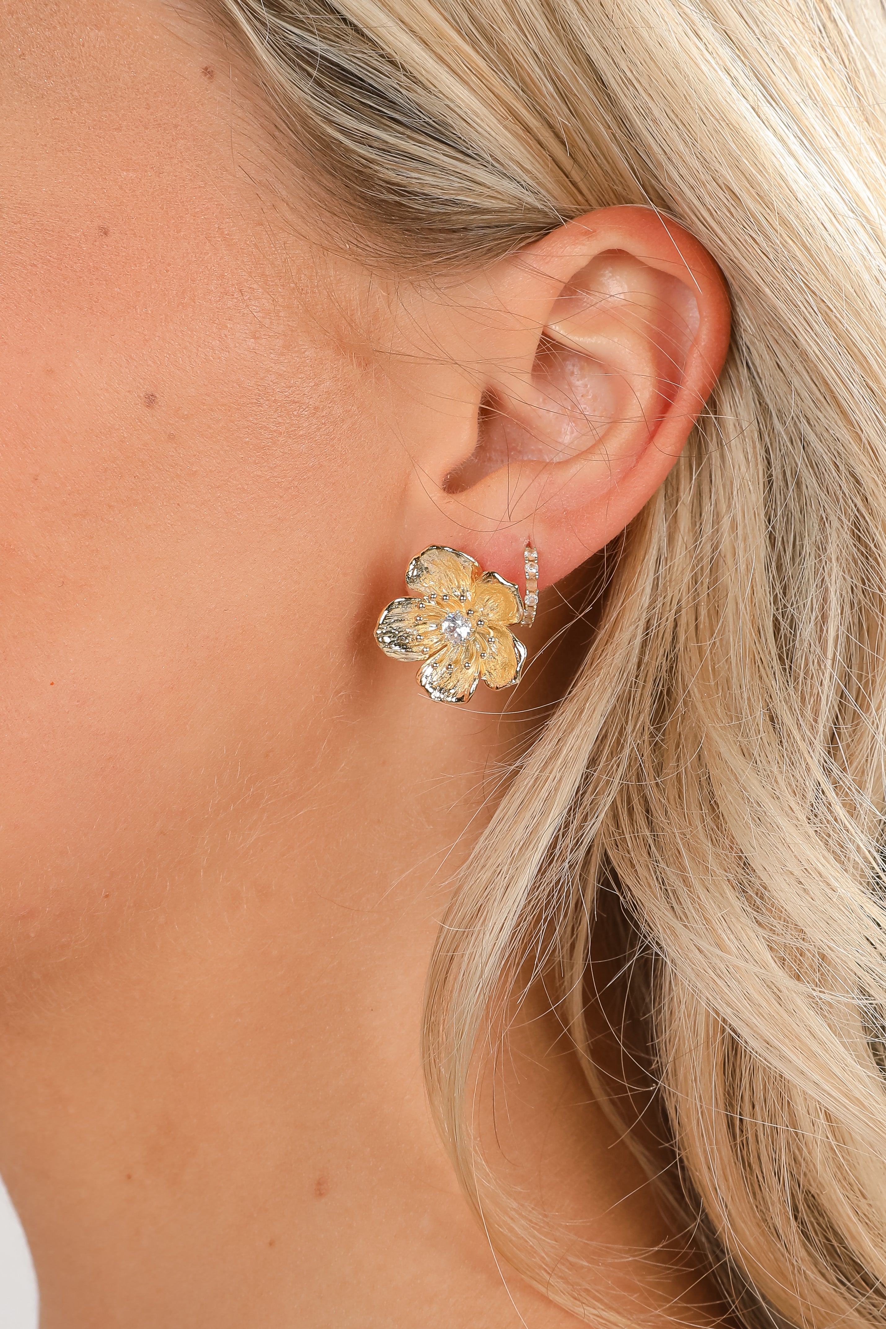 Close-up of a person wearing a floral earring with a blurred background