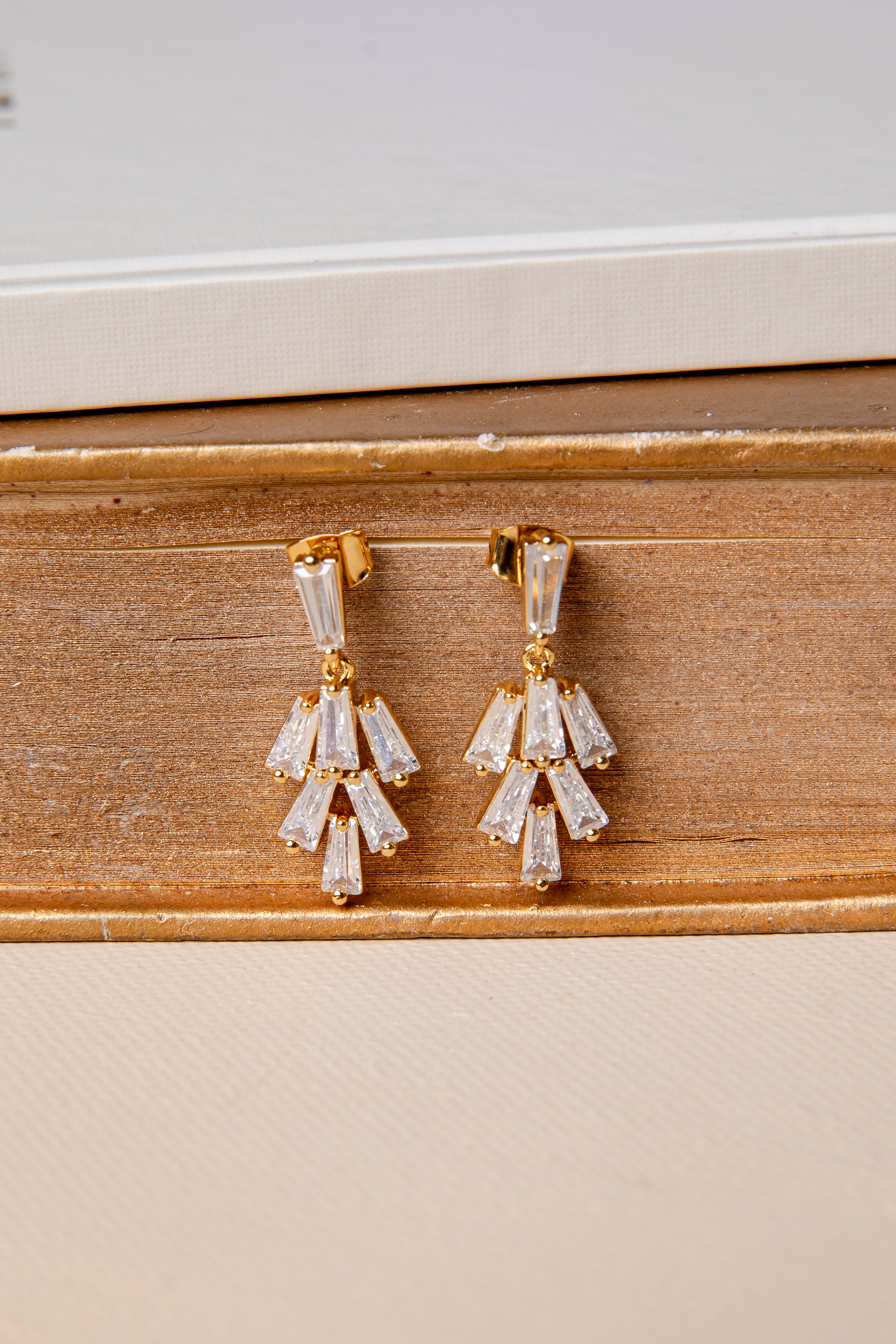 Gold and crystal earrings on a wooden surface