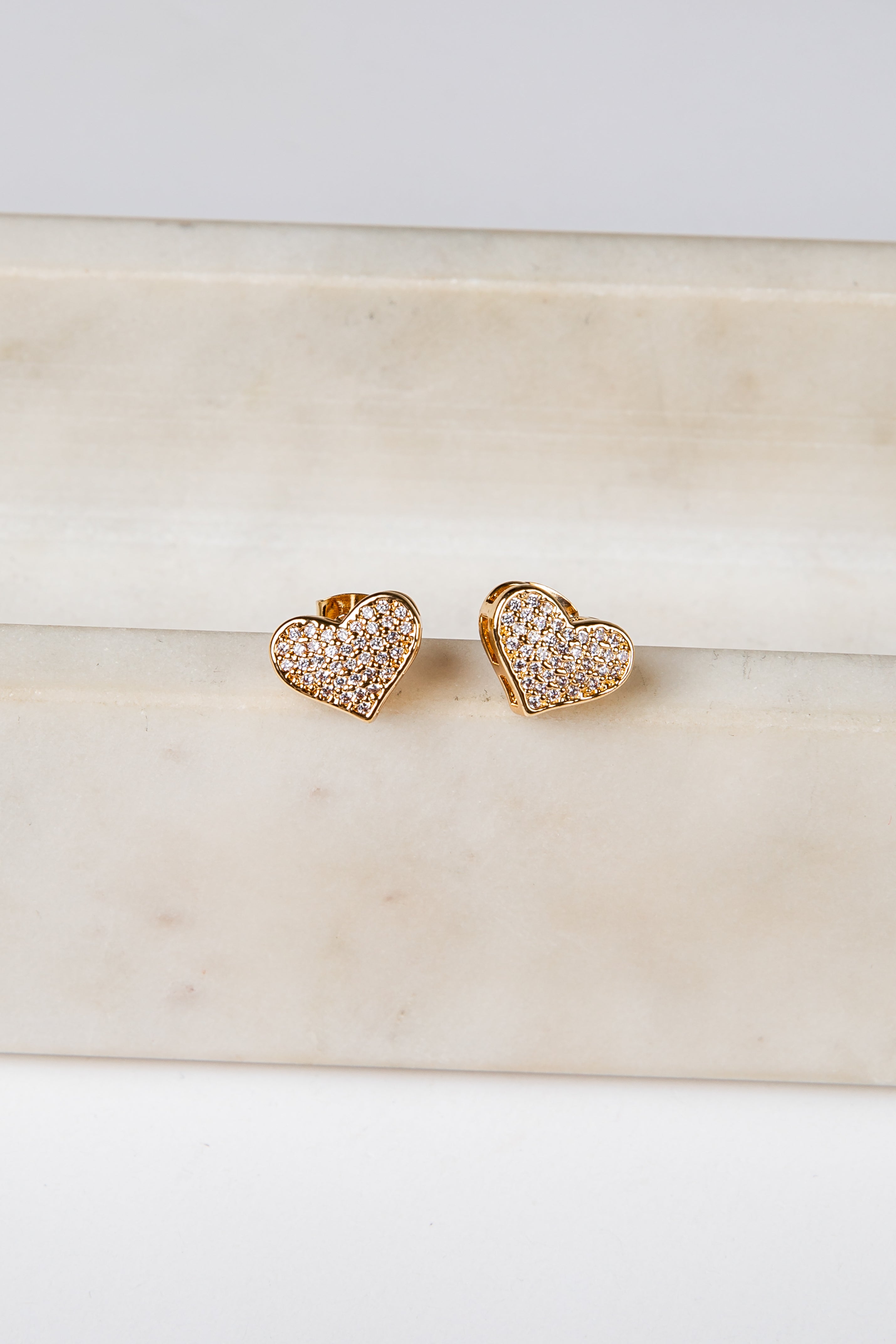 Heart-shaped gold earrings on a marble surface