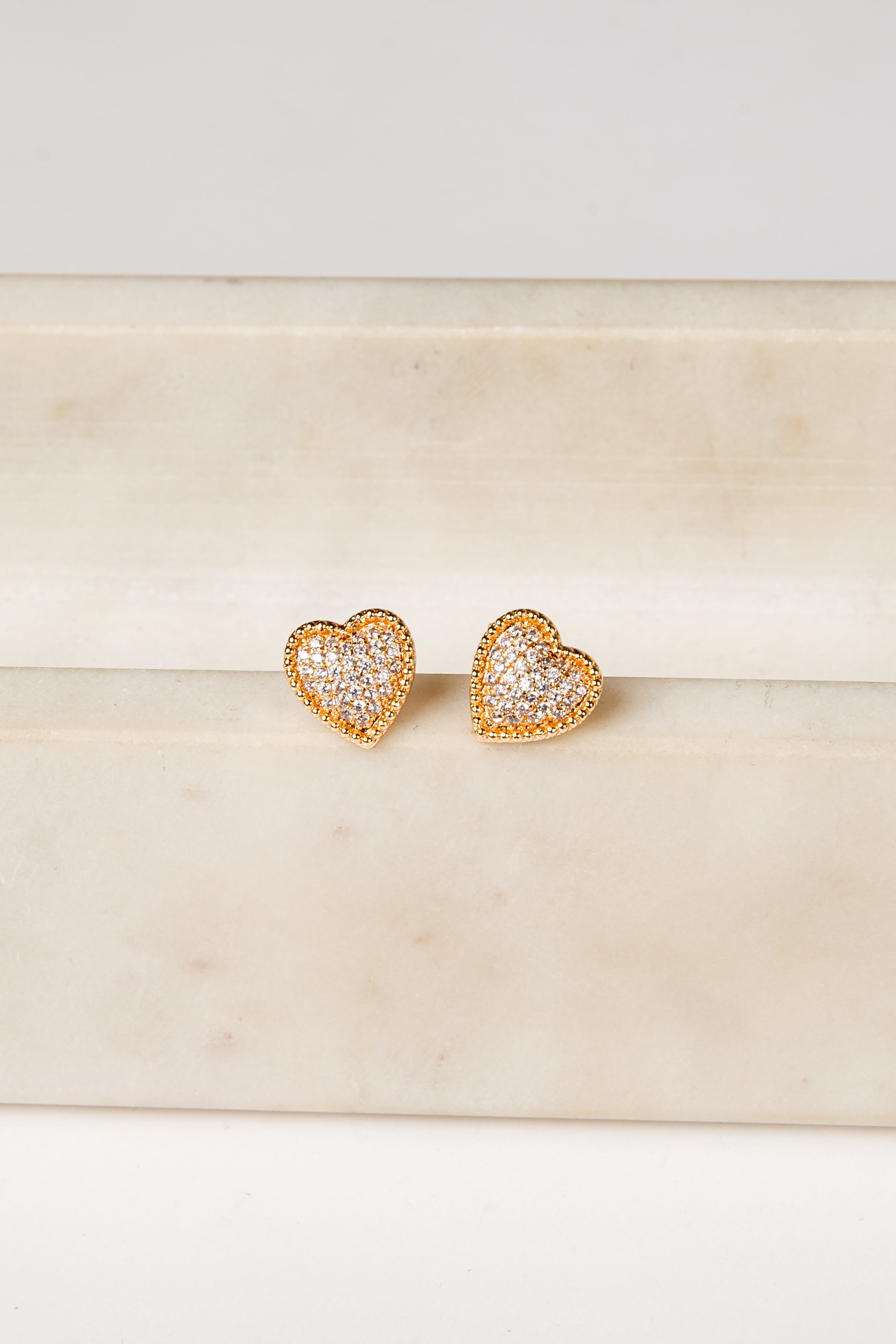 Heart-shaped gold earrings on a marble surface