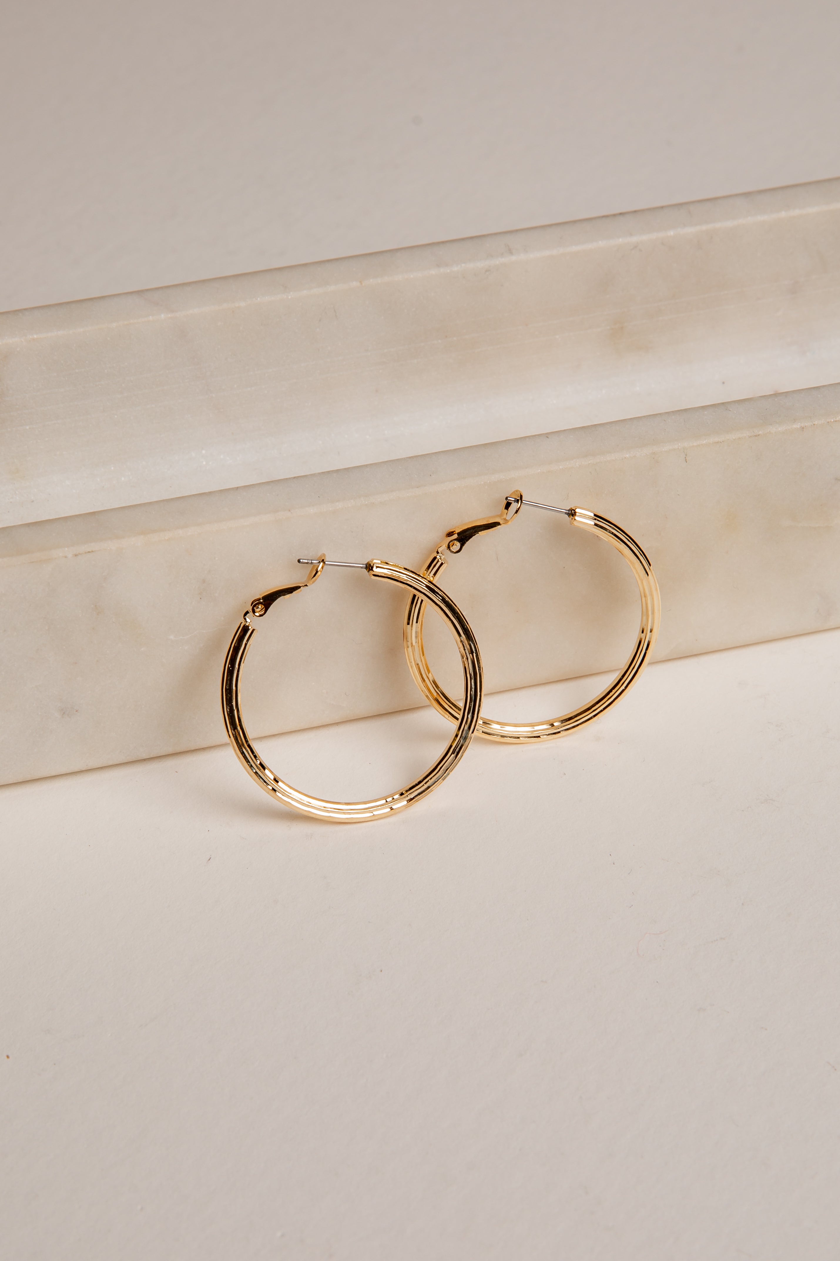 Gold hoop earrings on a light beige surface