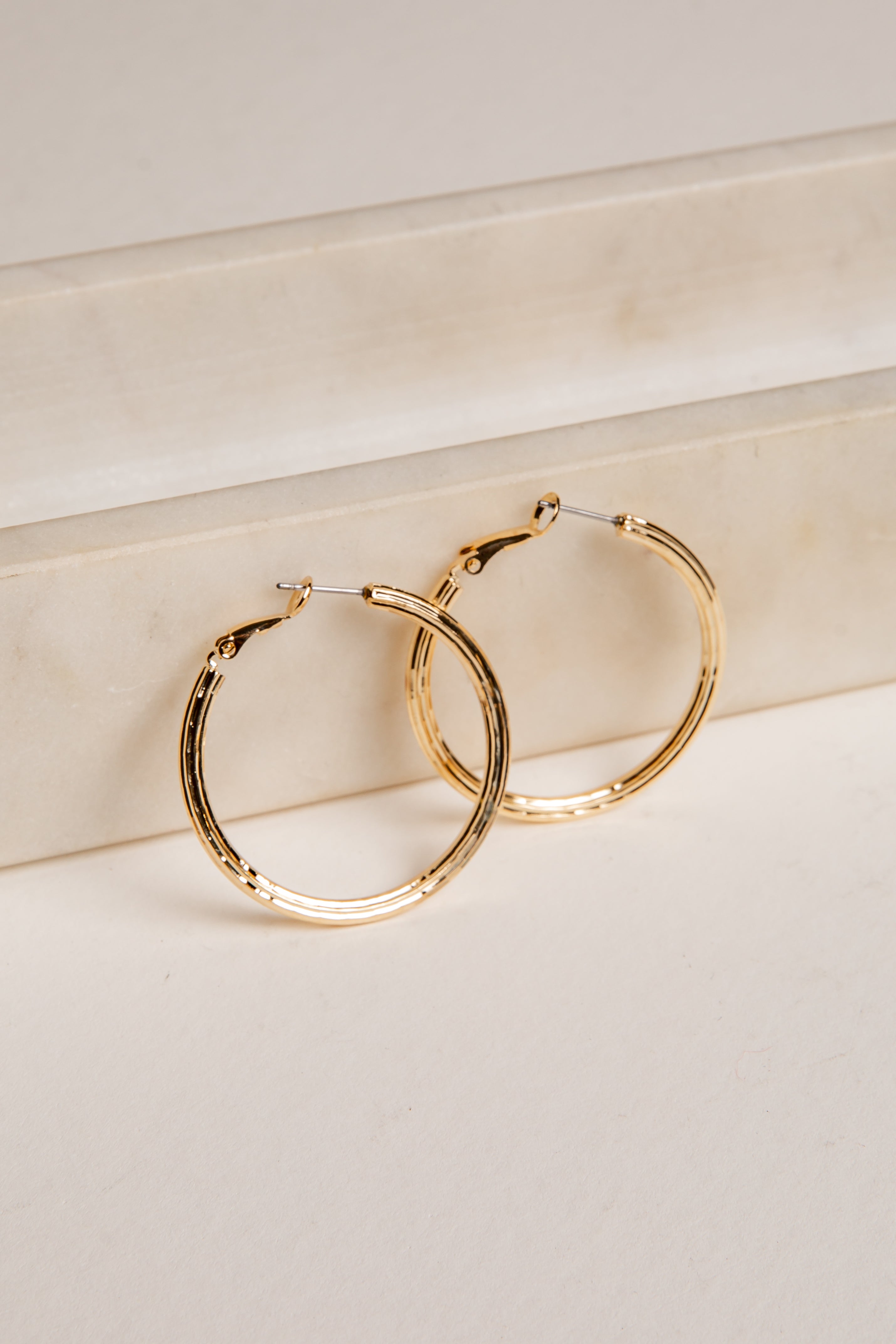 Gold hoop earrings on a light beige surface