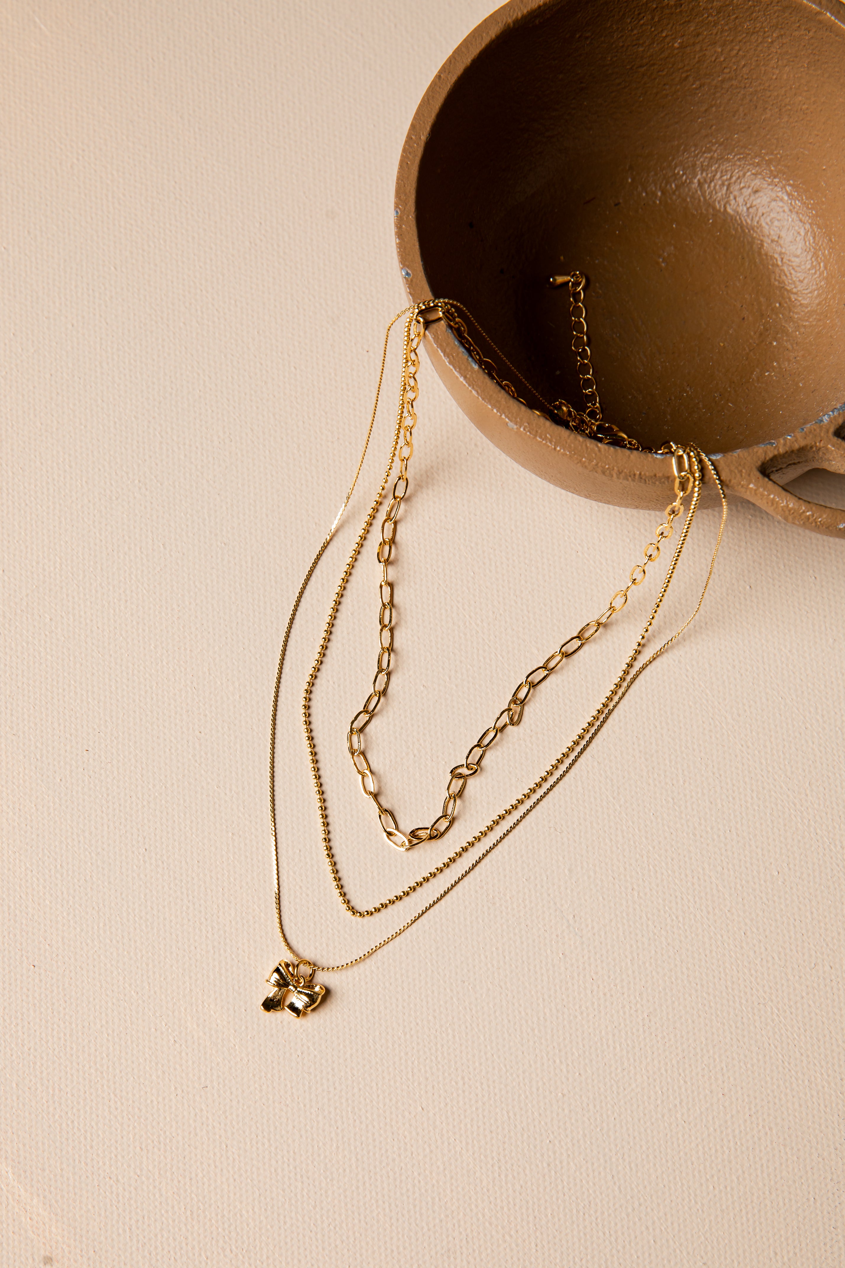 Gold necklaces with a pendant on a beige surface