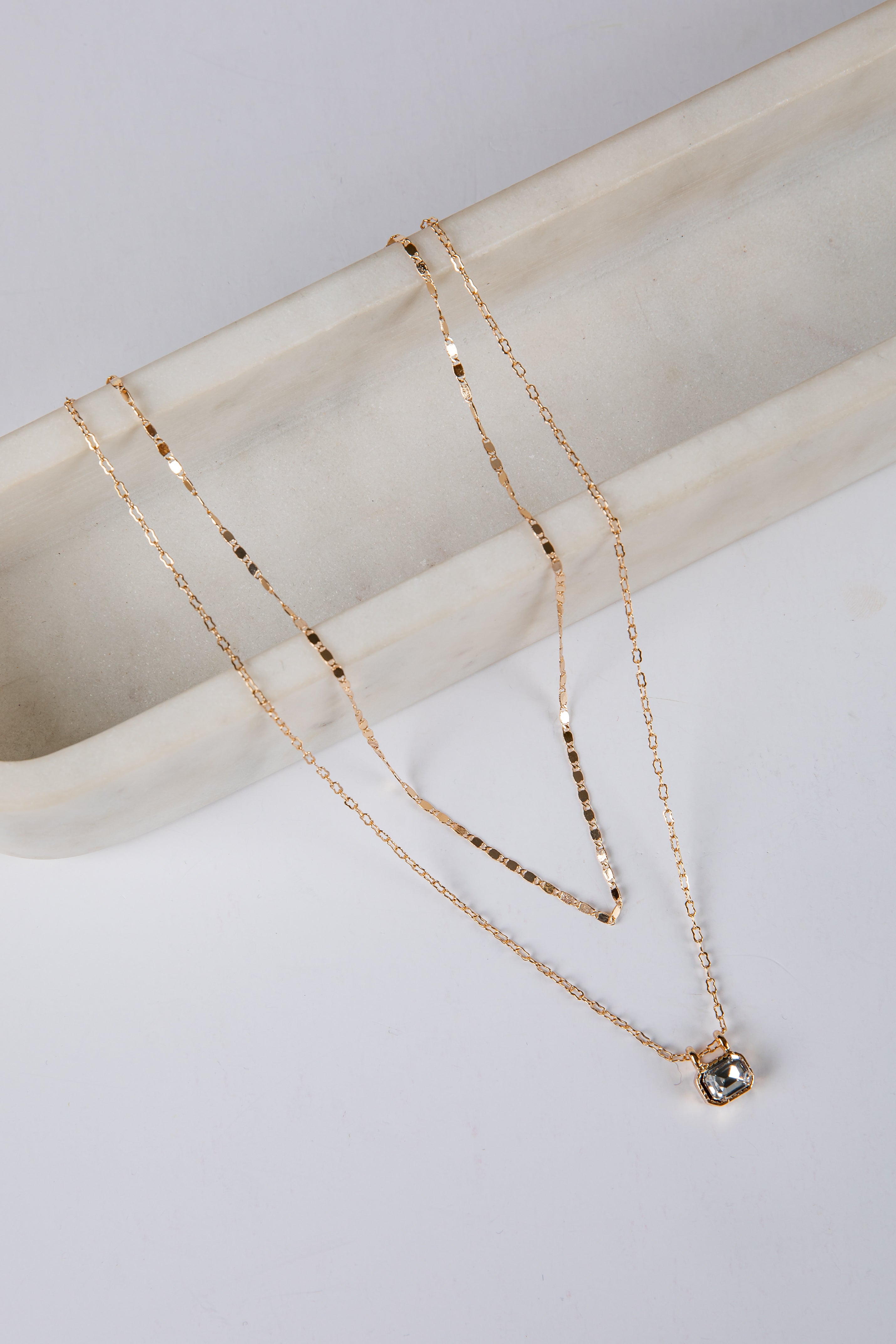 Gold necklace with a pendant on a marble surface