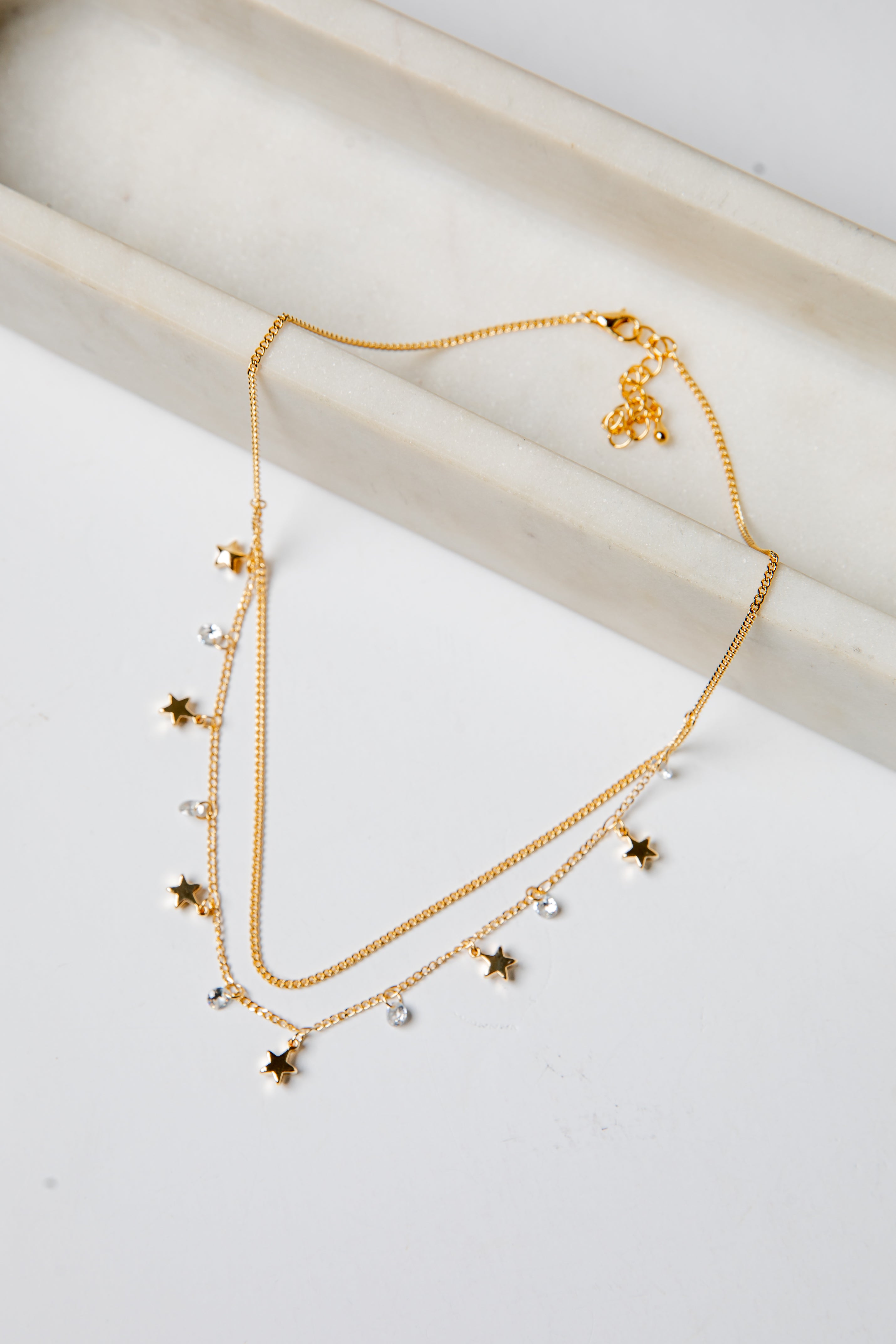 Gold necklace with star-shaped charms on a light background