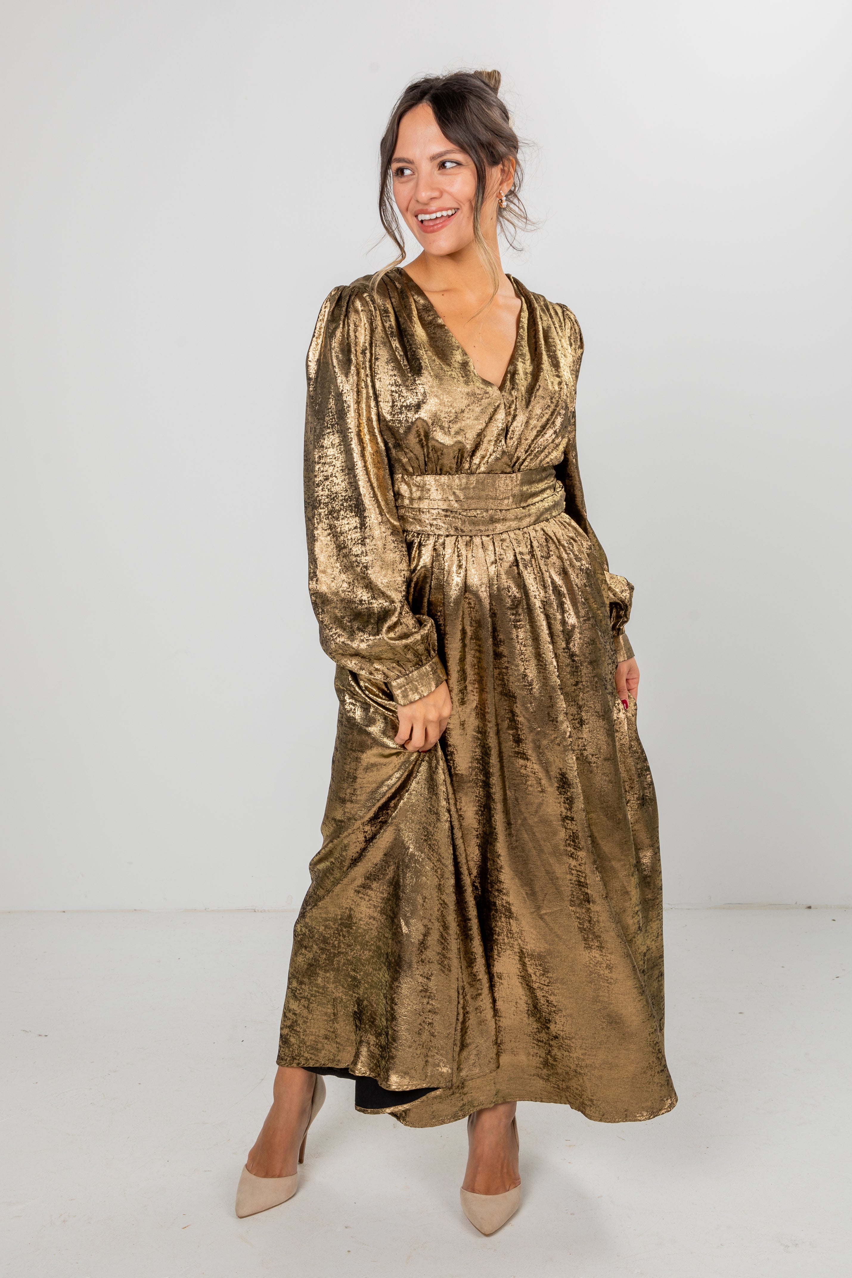 Woman wearing a gold metallic dress against a white background