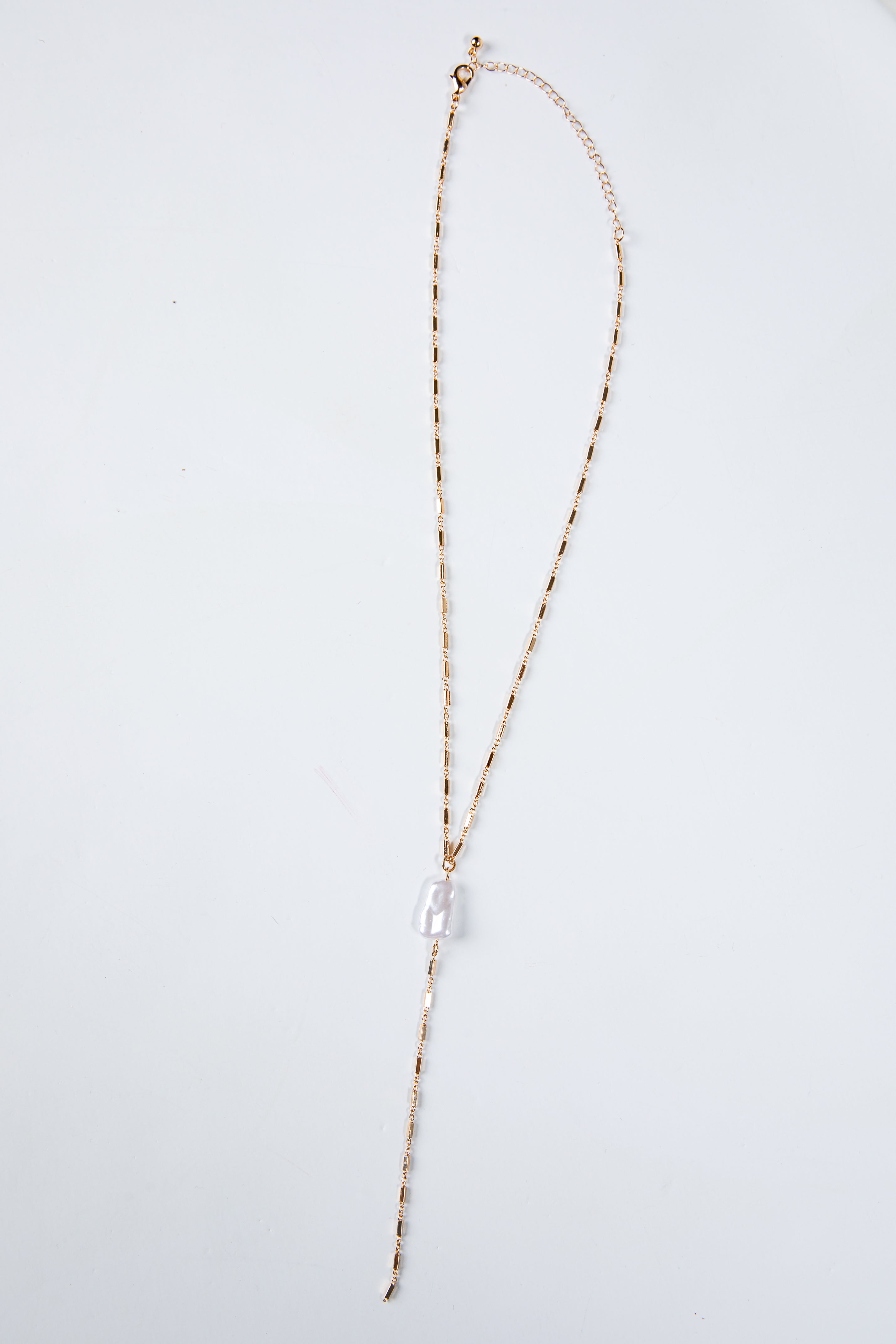 Long necklace with a clear pendant on a light gray background