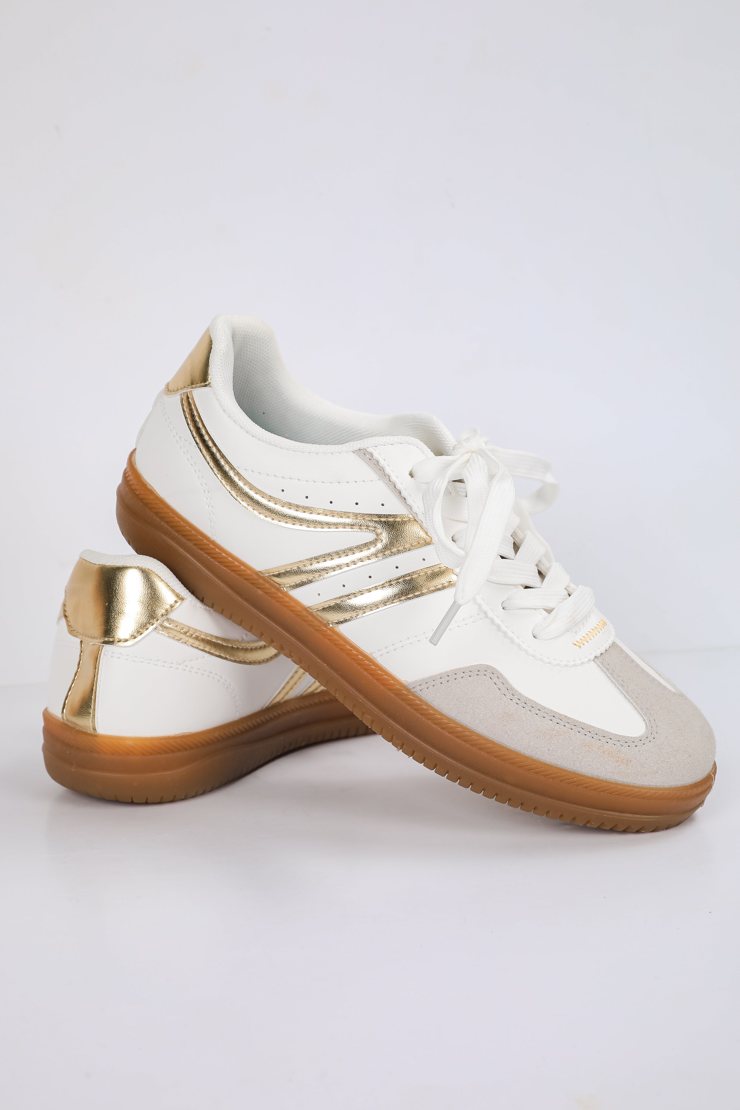 White sneakers with gold accents on a light gray background
