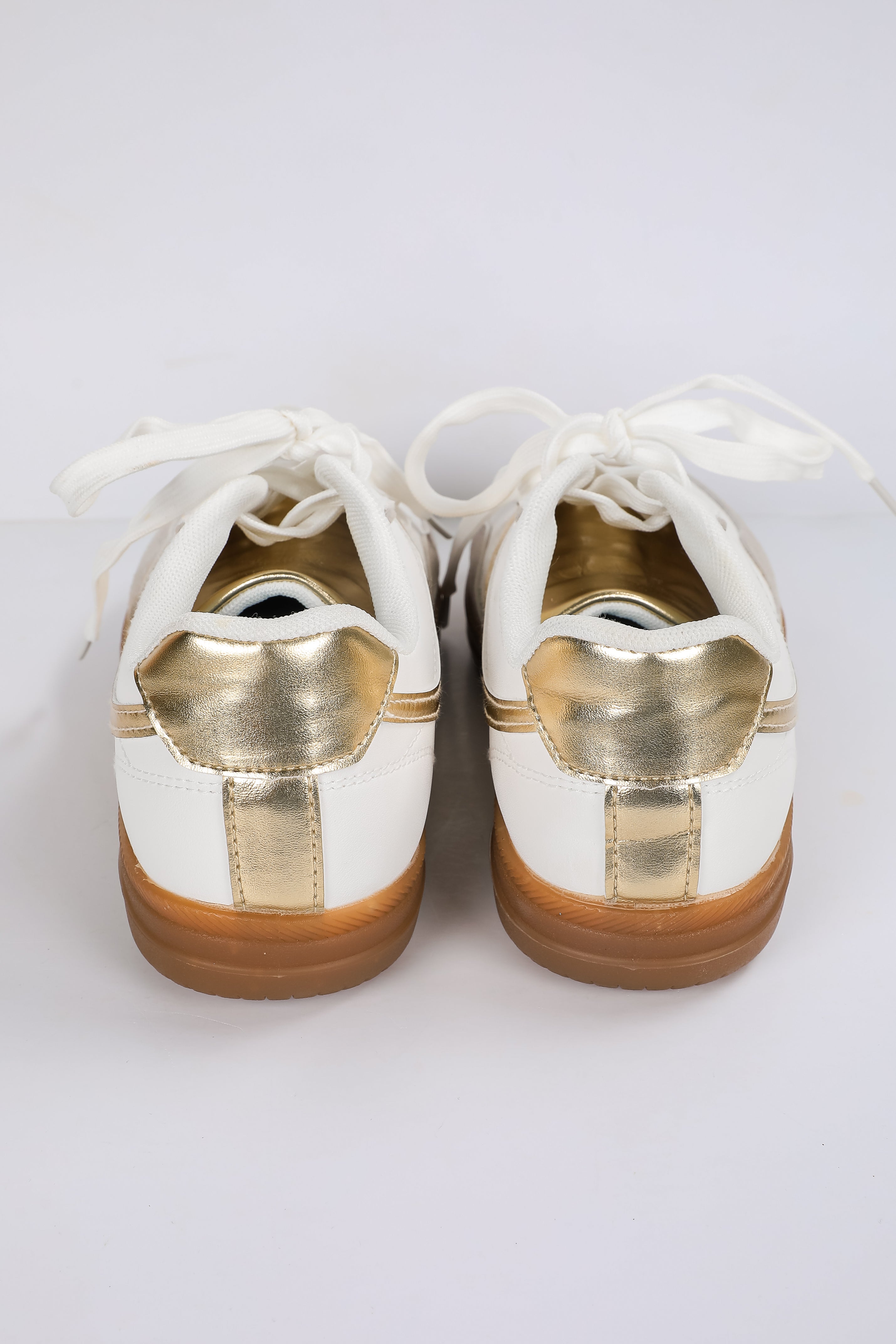 White sneakers with gold accents on a white background