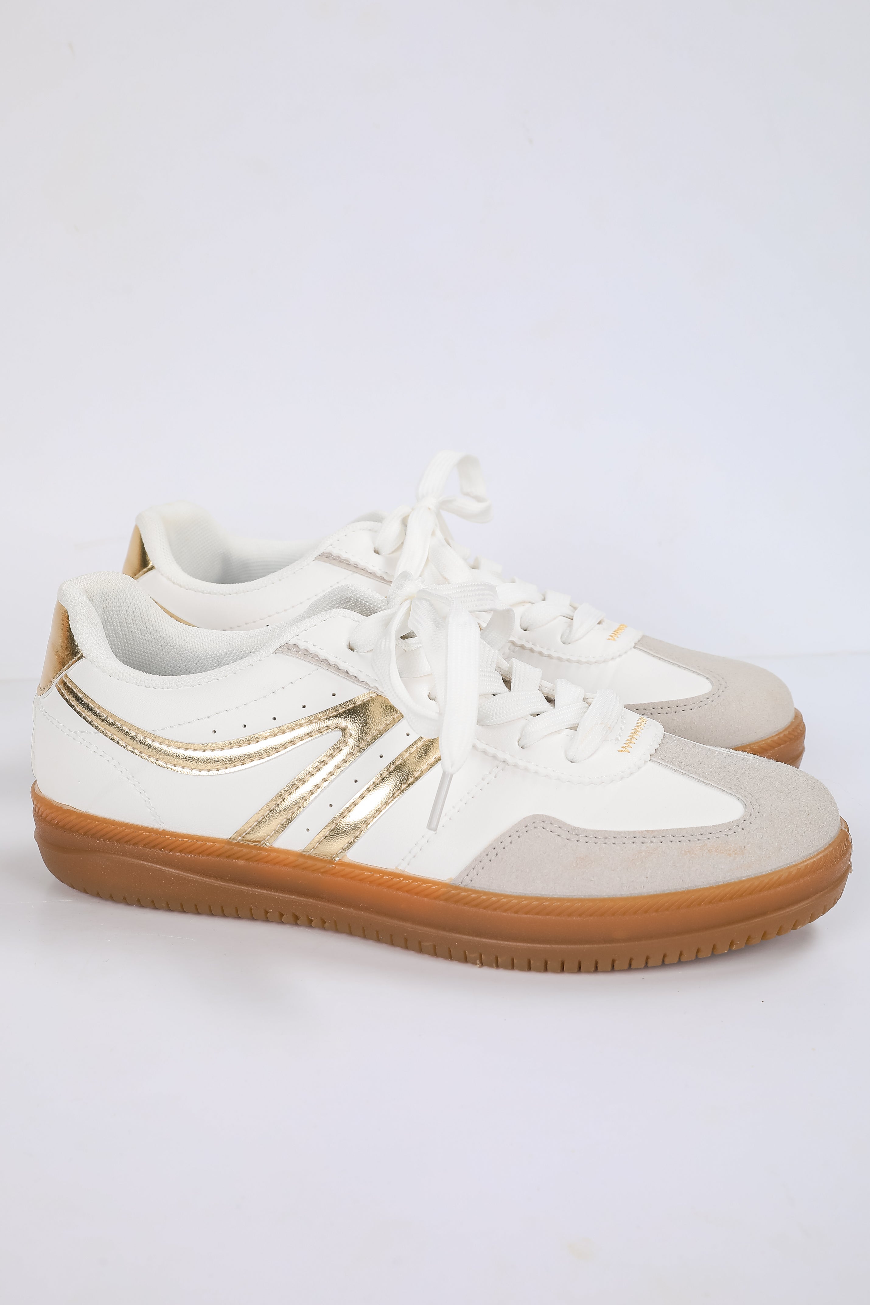 White sneakers with gold accents on a light gray background