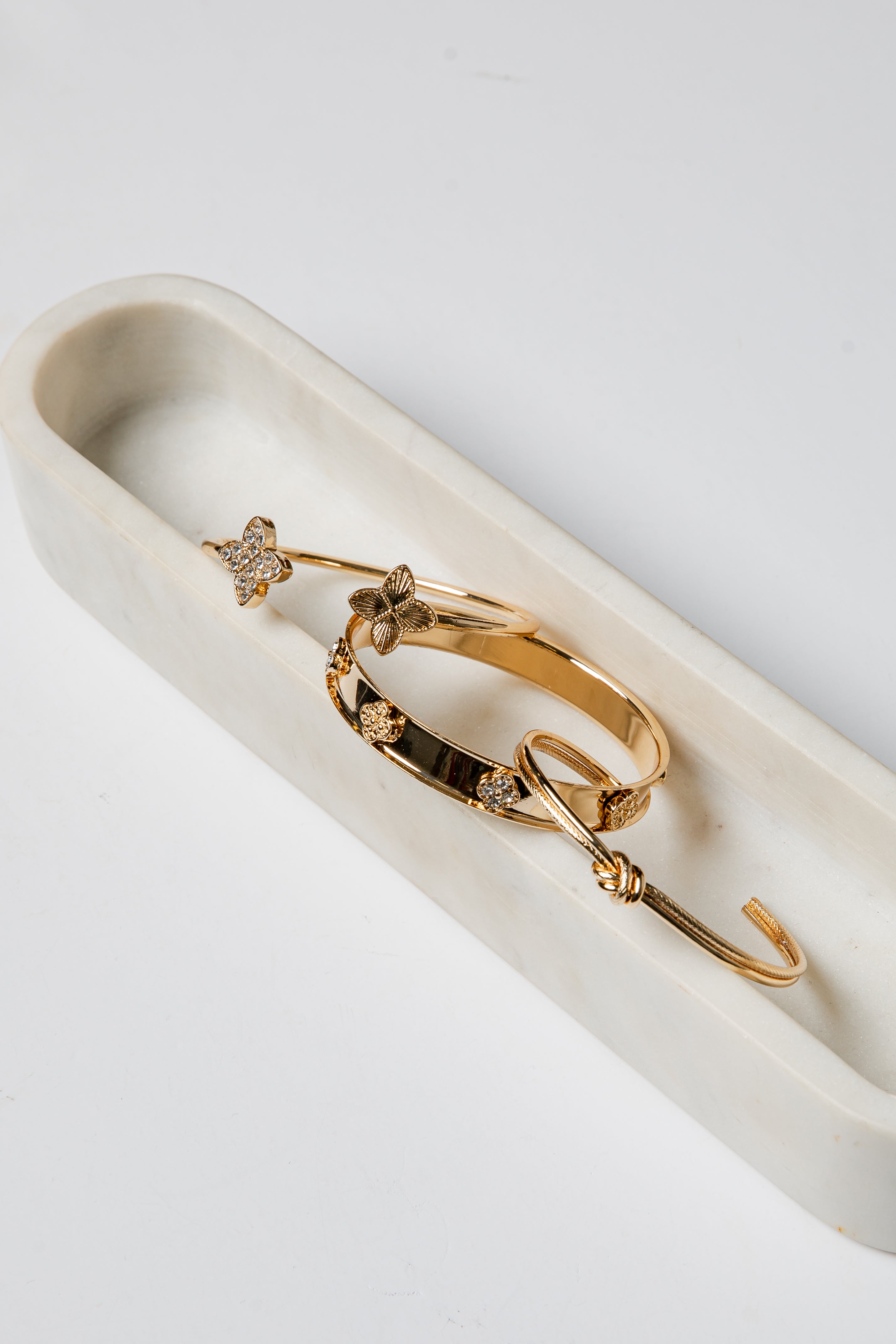 Gold bracelet with floral designs on a white dish