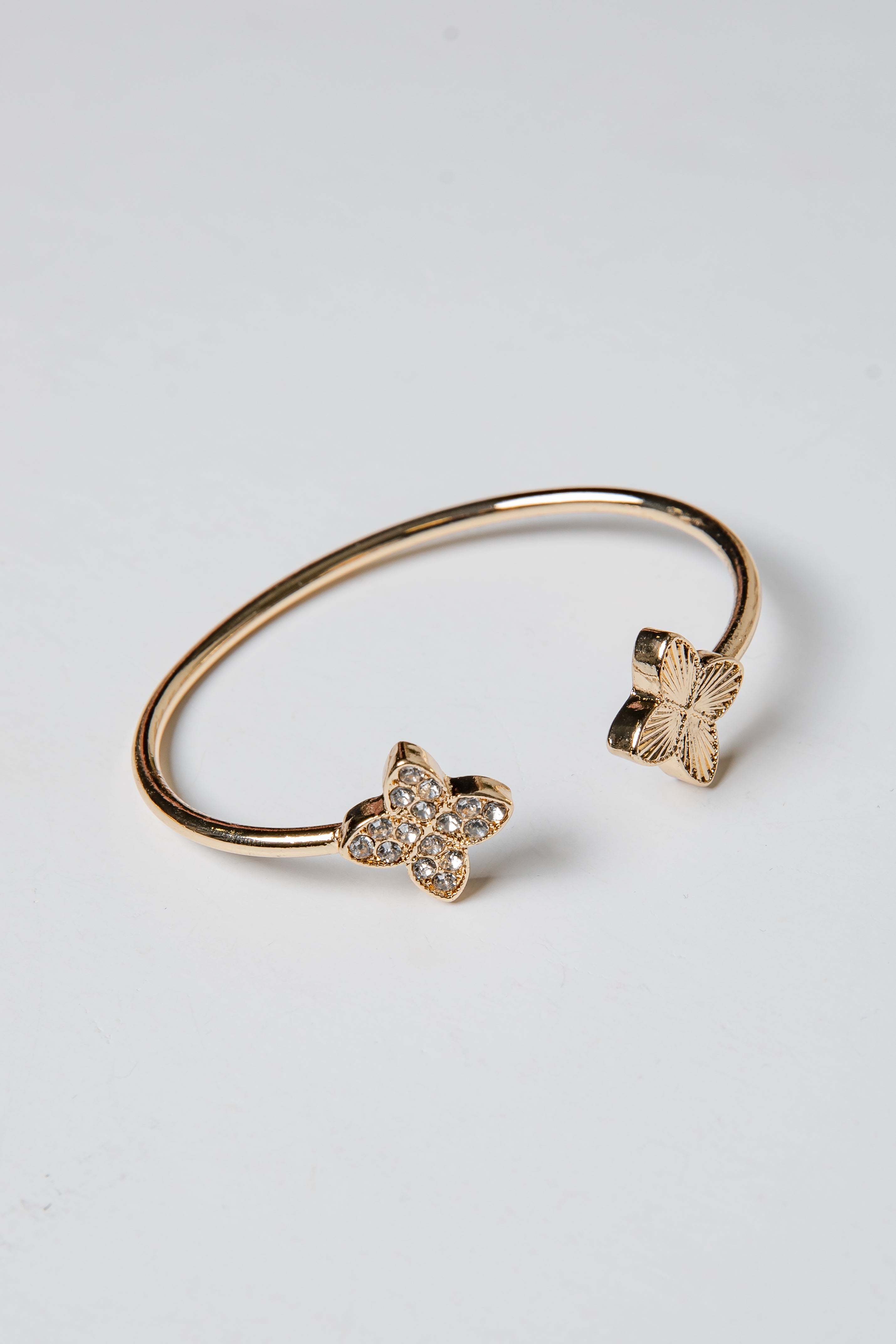 Gold bracelet with butterfly charms on a light gray background