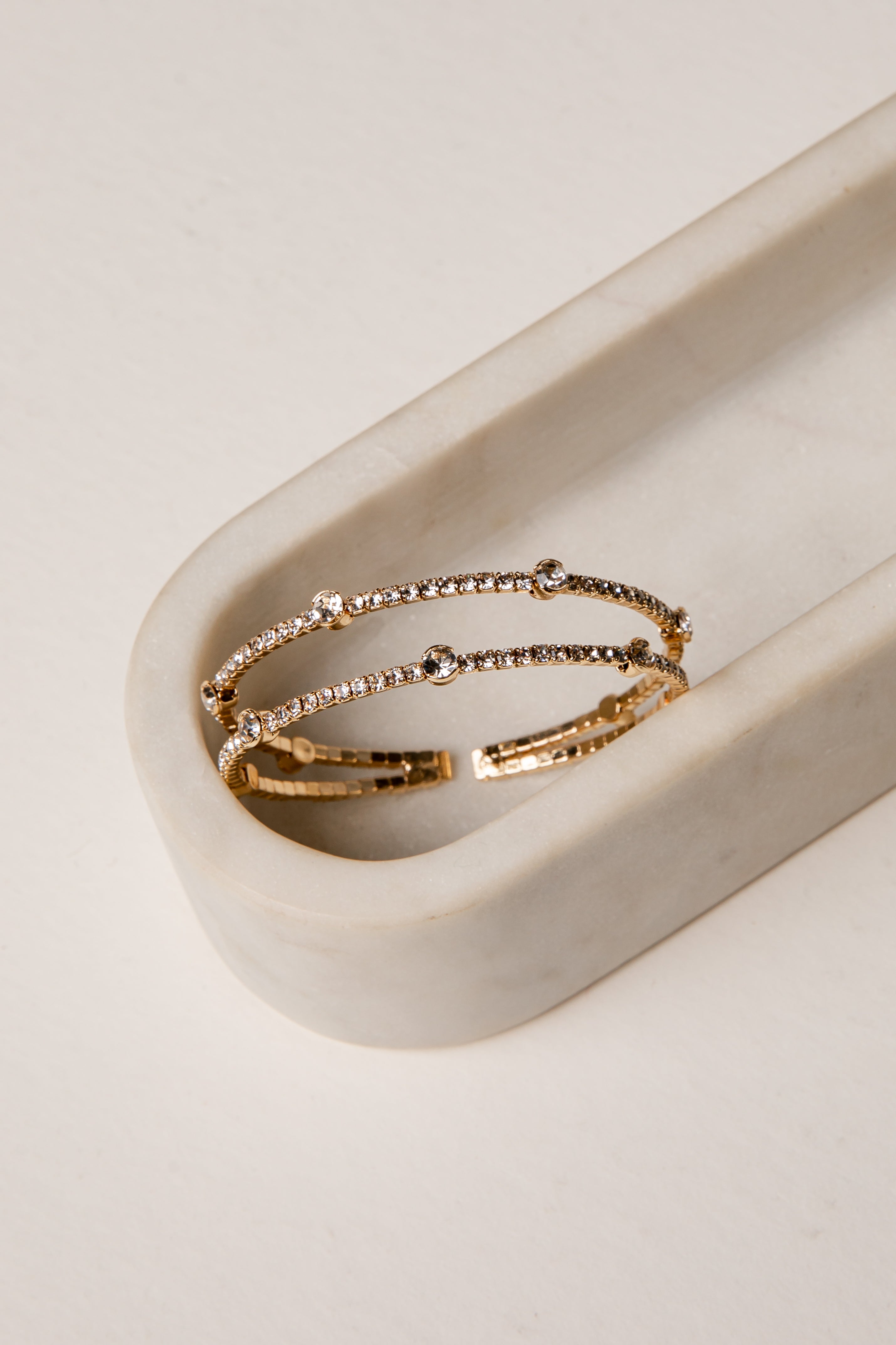 Gold hoop bracelet on a white marble surface