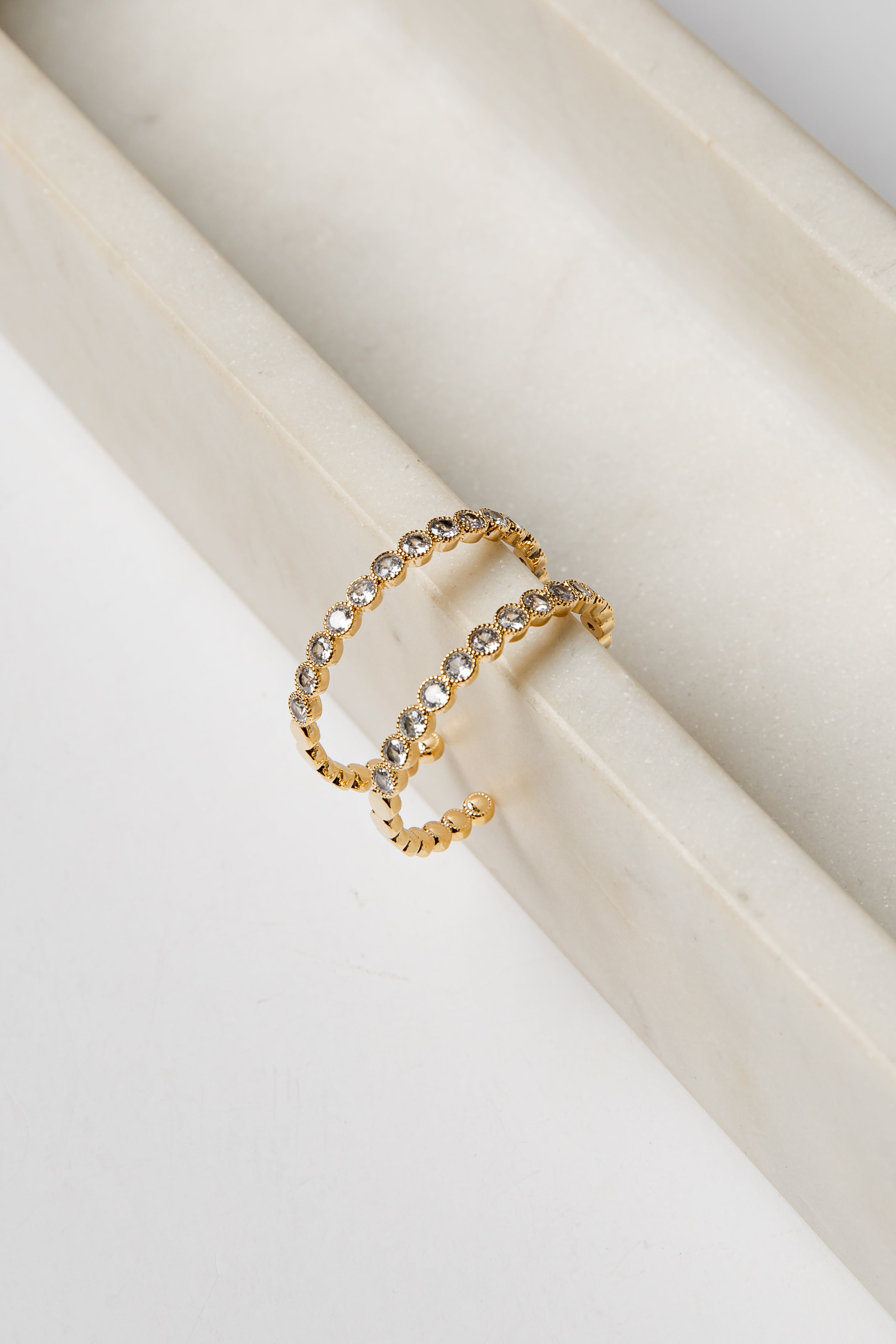 Gold earrings with embedded stones on a white surface